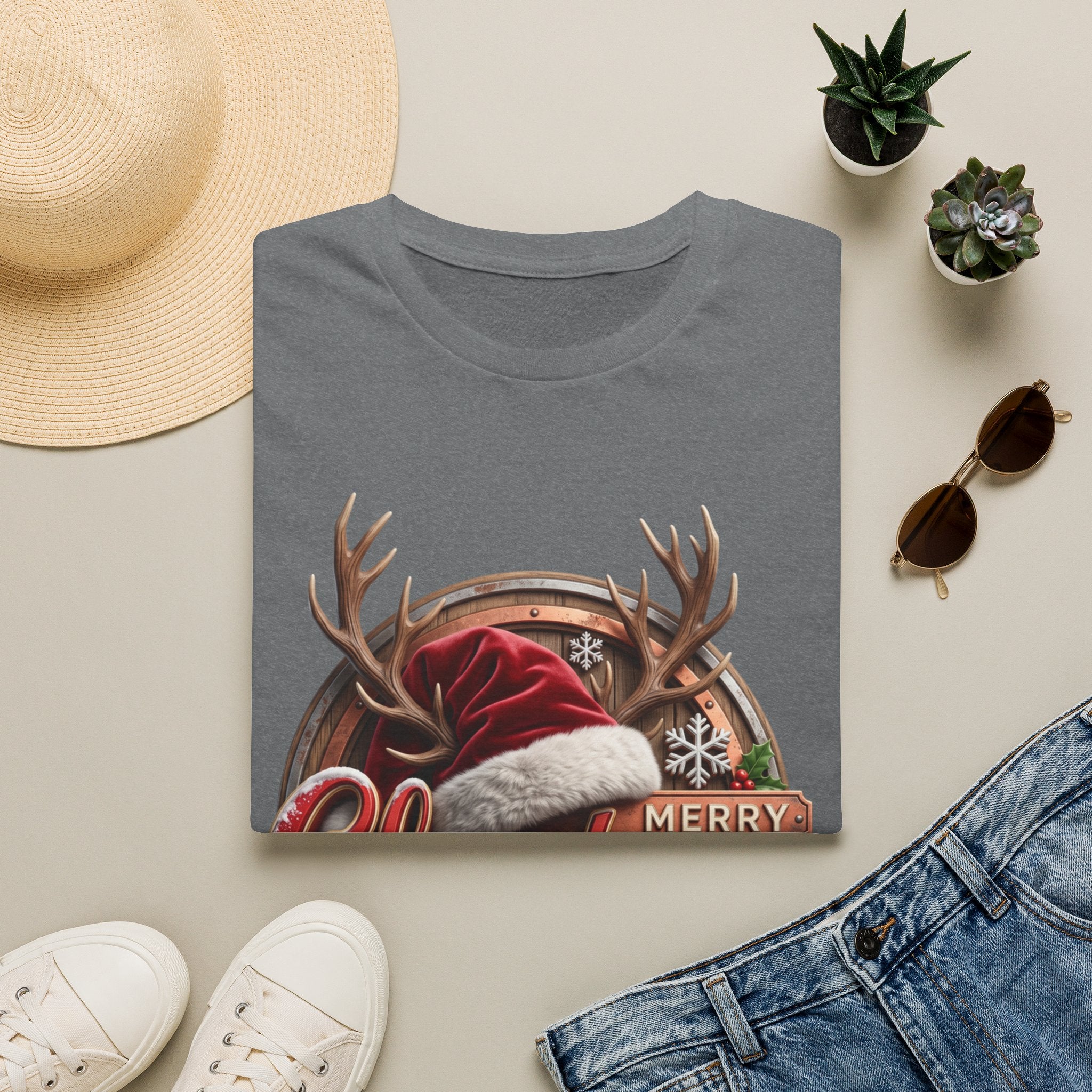 Merry Christmas Vintage Santa Hat & Antlers print on a Graphite Heather t-shirt, folded beside a straw hat and jeans