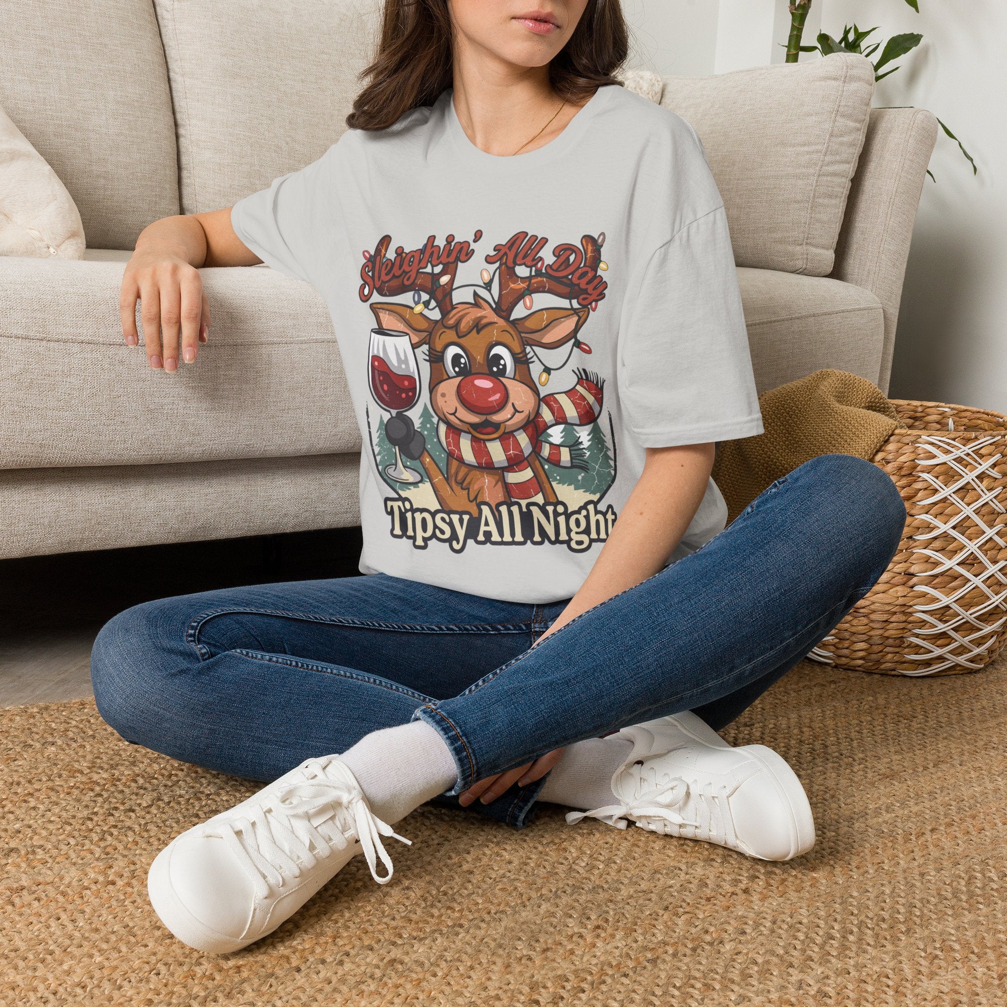 Reindeer Sleighin' All Day Tipsy All Night t-shirt in Ice Grey, worn by a woman seated on a rug