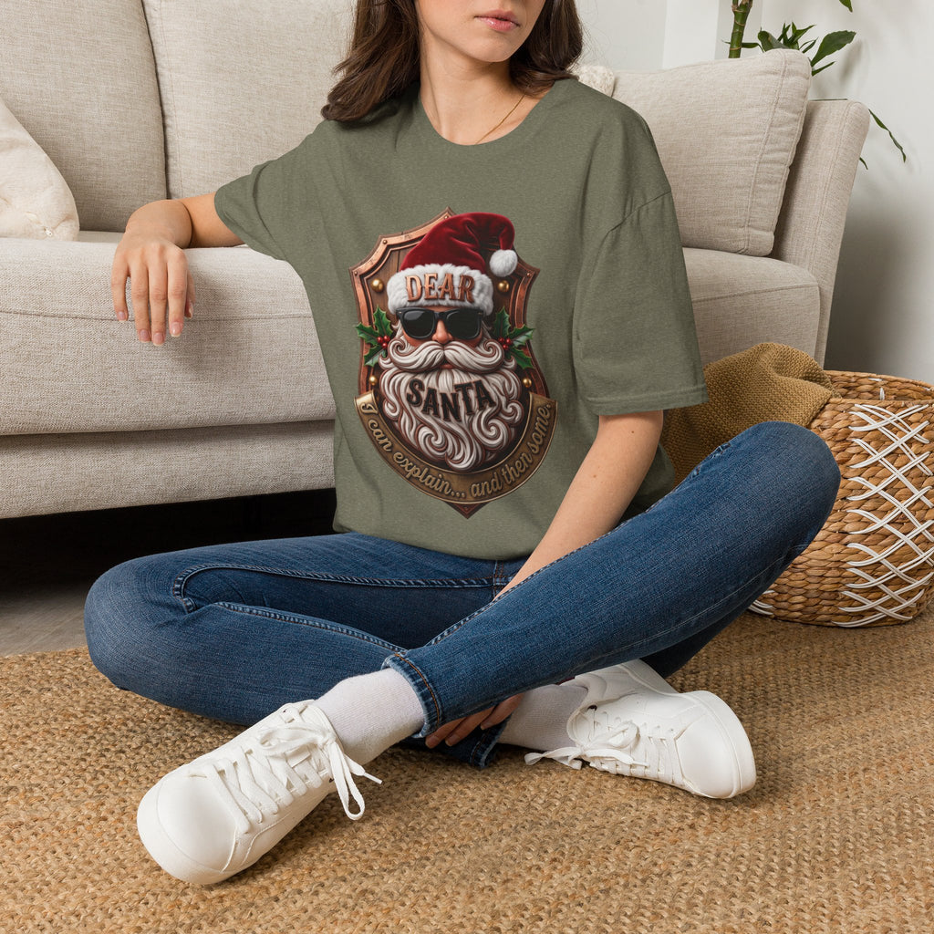Dear Santa I Can Explain Sunglasses Crest t-shirt in Heather Military Green, worn by a woman seated on a rug