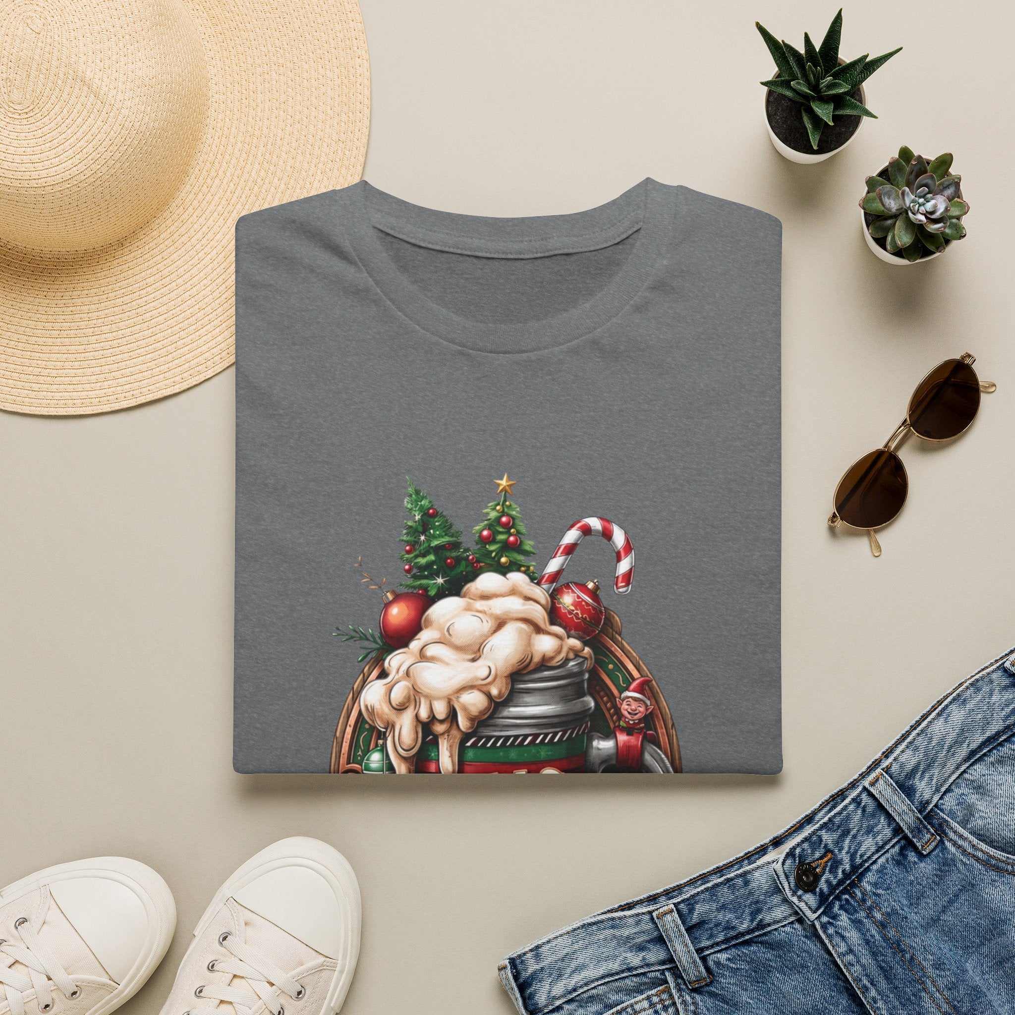 XMAS Beer Pour Me a Very Merry Christmas print on a Graphite Heather t-shirt, folded beside a straw hat and jeans