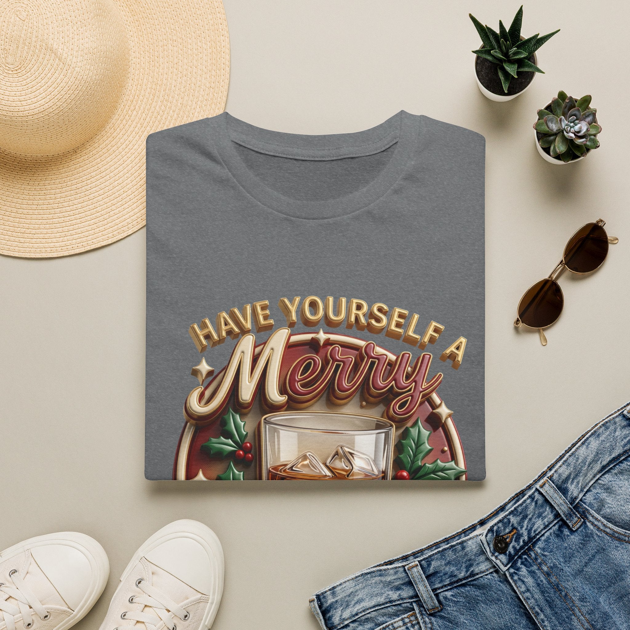Have Yourself a Merry Little Cocktail print on a Graphite Heather t-shirt, folded beside a straw hat and jeans