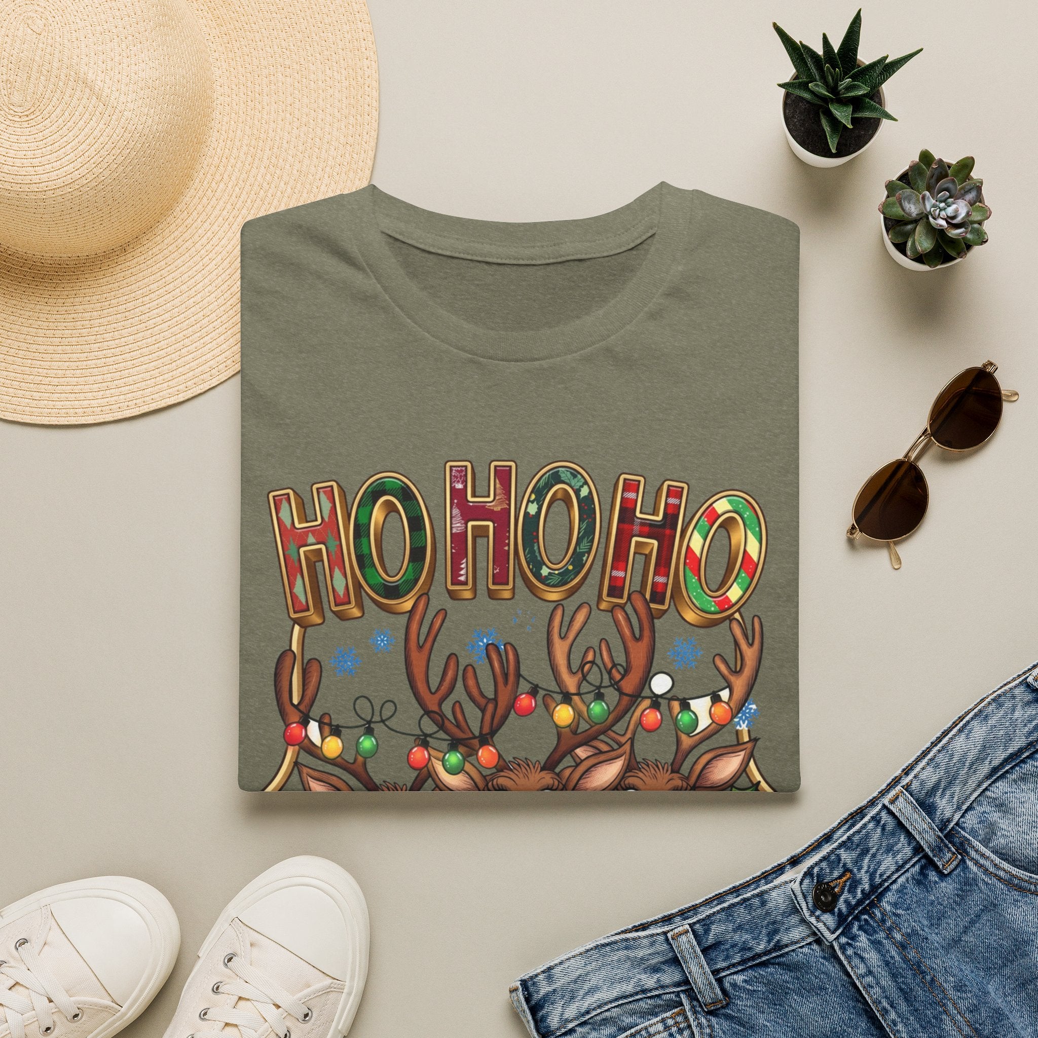 Reindeer Trio Ho Ho Ho Christmas Lights print on a Heather Military Green t-shirt, folded beside a straw hat and jeans