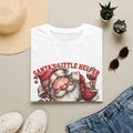 Santa's Little Helper Is Lit Christmas Wine print on a White t-shirt, folded beside a straw hat and jeans