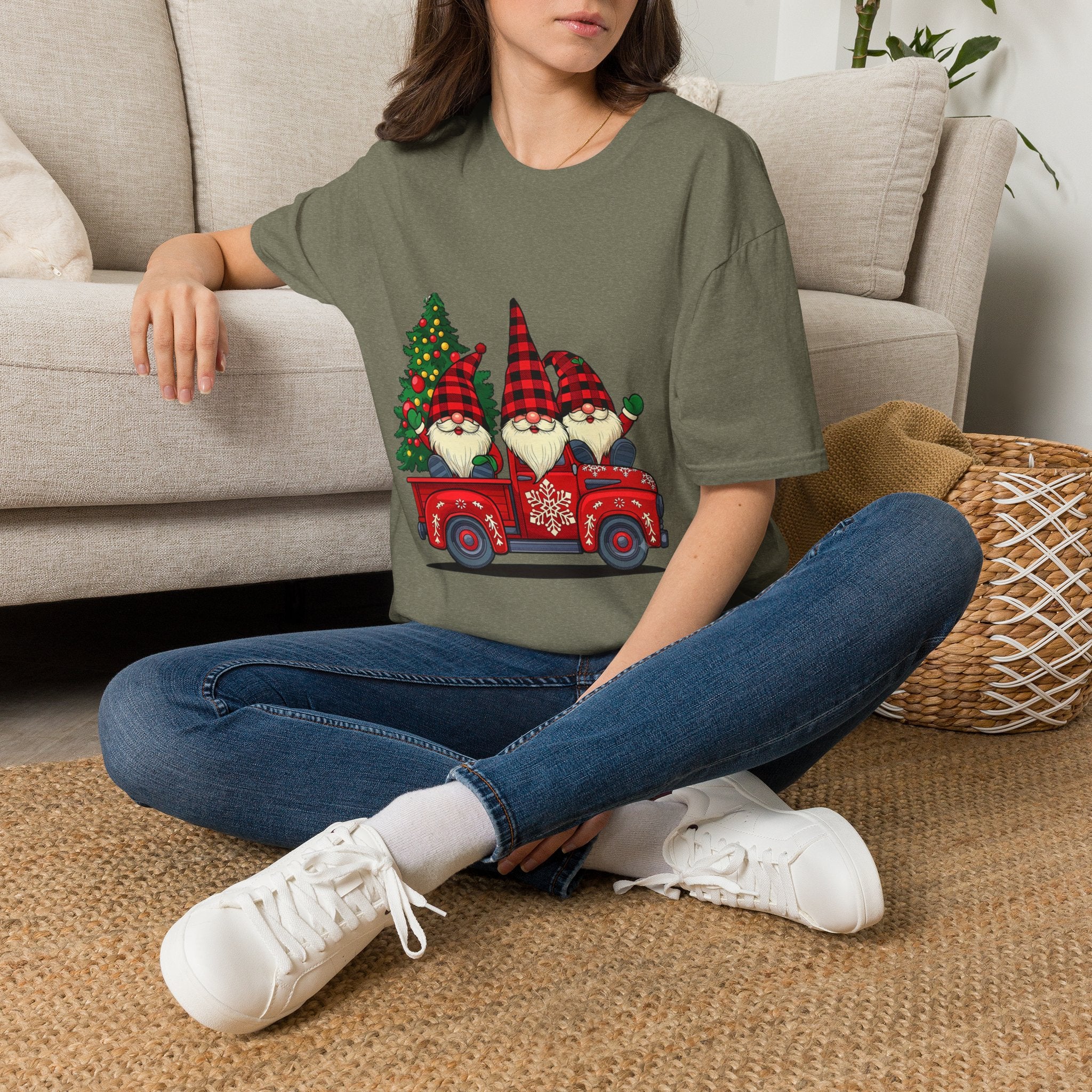 Buffalo Plaid Gnomes Red Truck t-shirt in Heather Military Green, worn by a woman seated on a rug