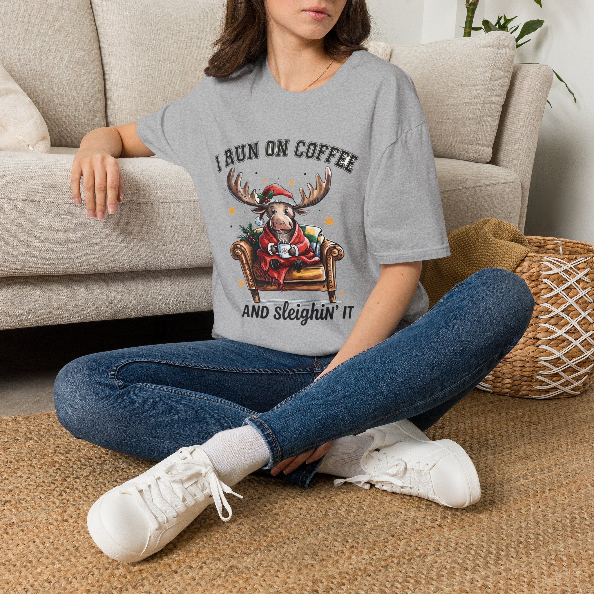 Moose I Run On Coffee and Sleighin' It t-shirt in Sport Grey, worn by a woman seated on a rug