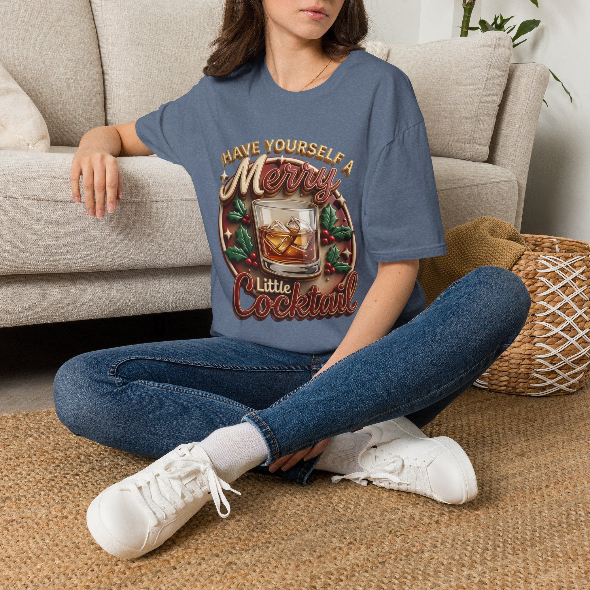 Have Yourself a Merry Little Cocktail t-shirt in Heather Indigo, worn by a woman seated on a rug
