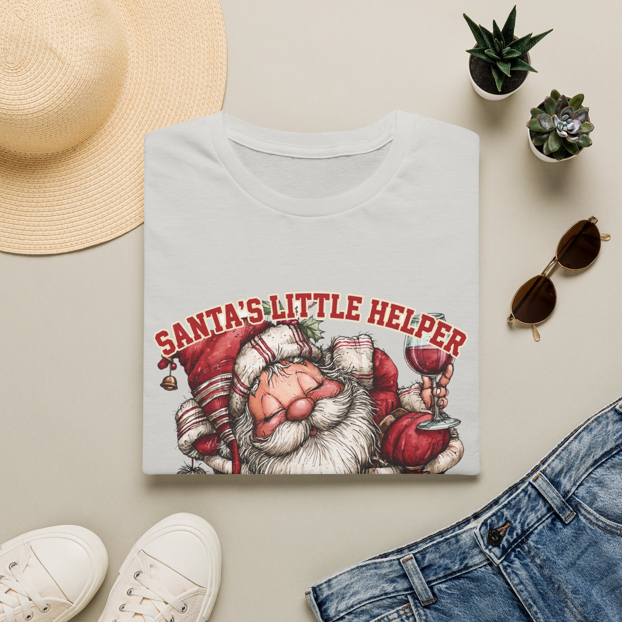Santa's Little Helper Is Lit Christmas Wine print on an Ice Grey t-shirt, folded beside a straw hat and jeans