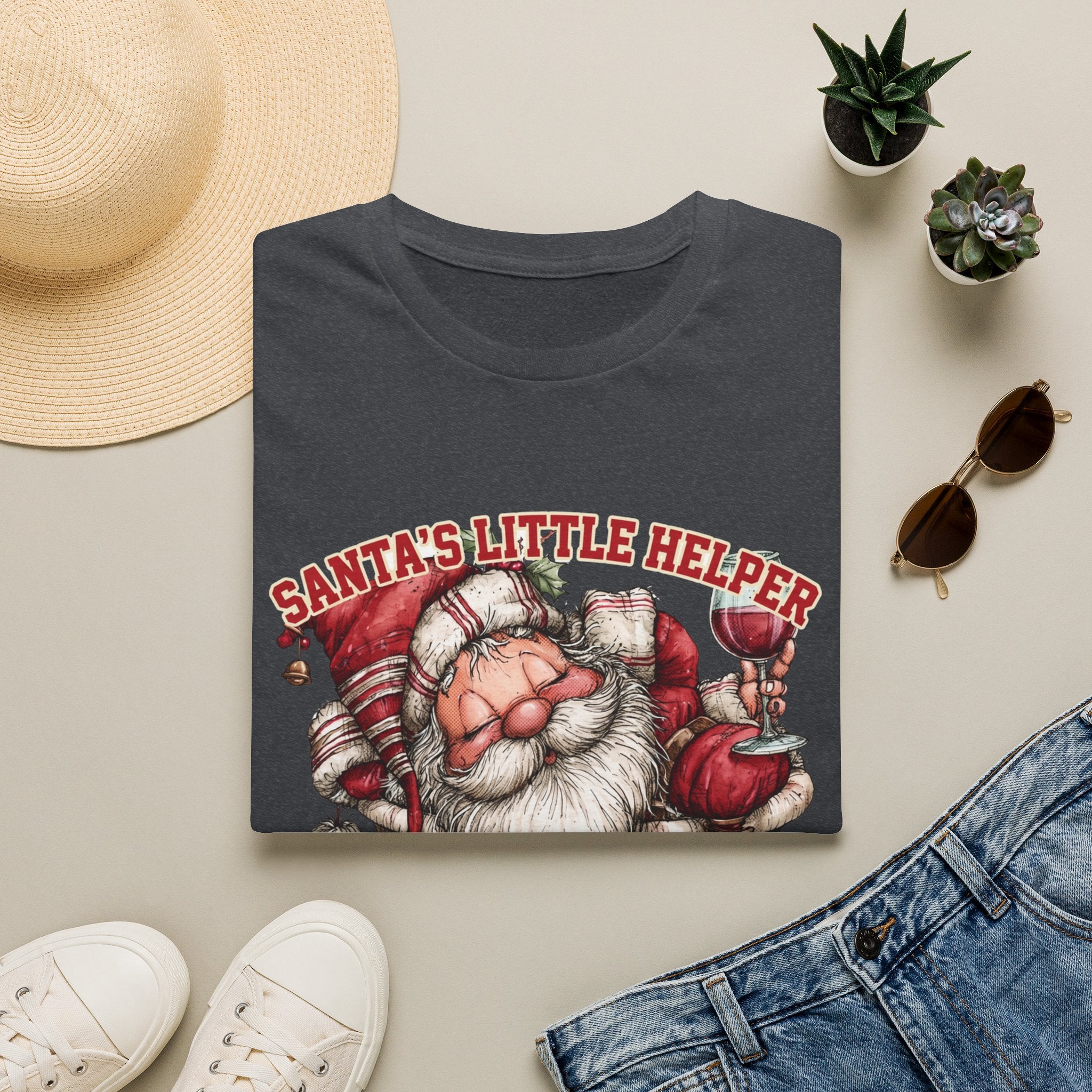 Santa's Little Helper Is Lit Christmas Wine print on a Dark Heather Grey t-shirt, folded beside a straw hat and jeans