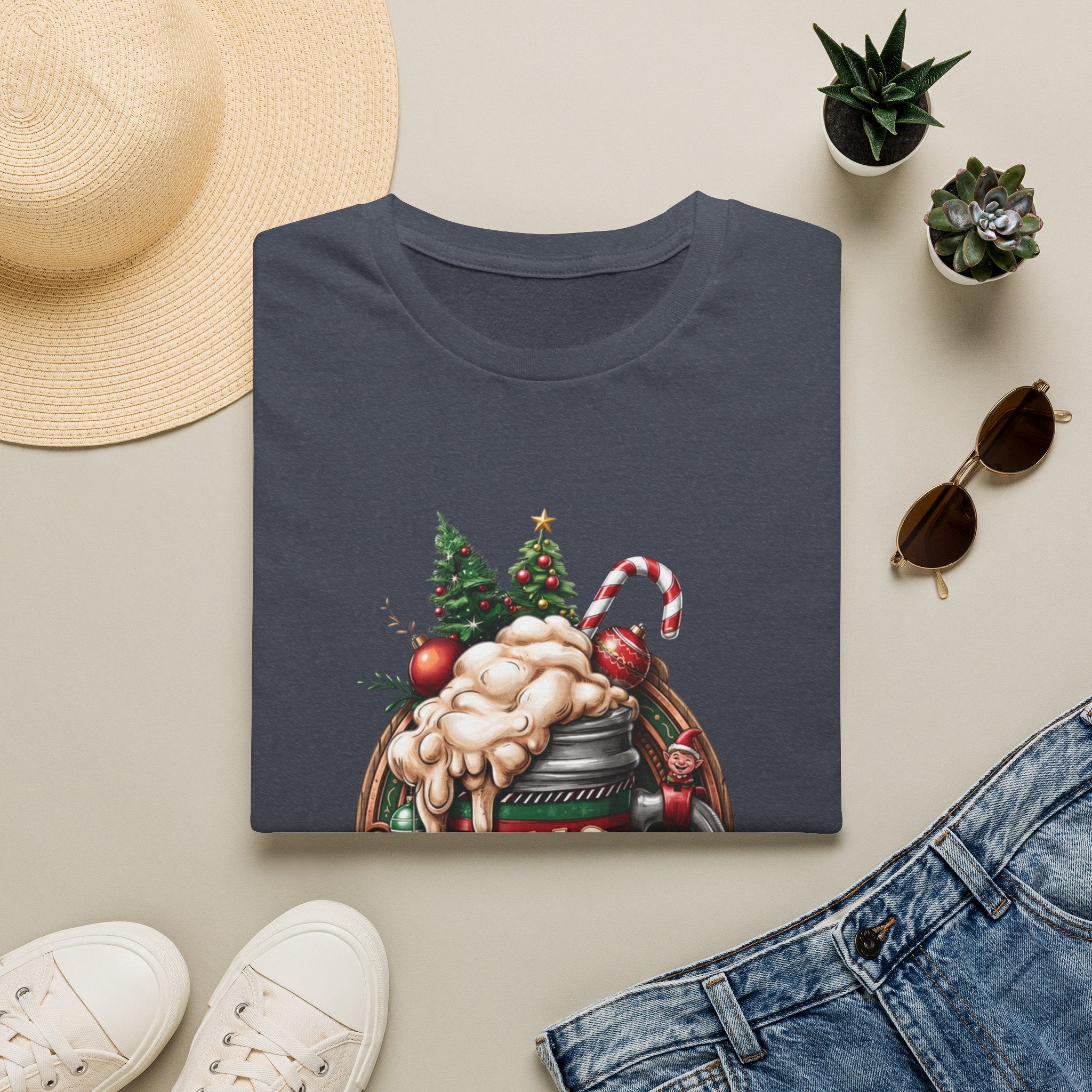 XMAS Beer Pour Me a Very Merry Christmas print on a Heather Navy t-shirt, folded beside a straw hat and jeans