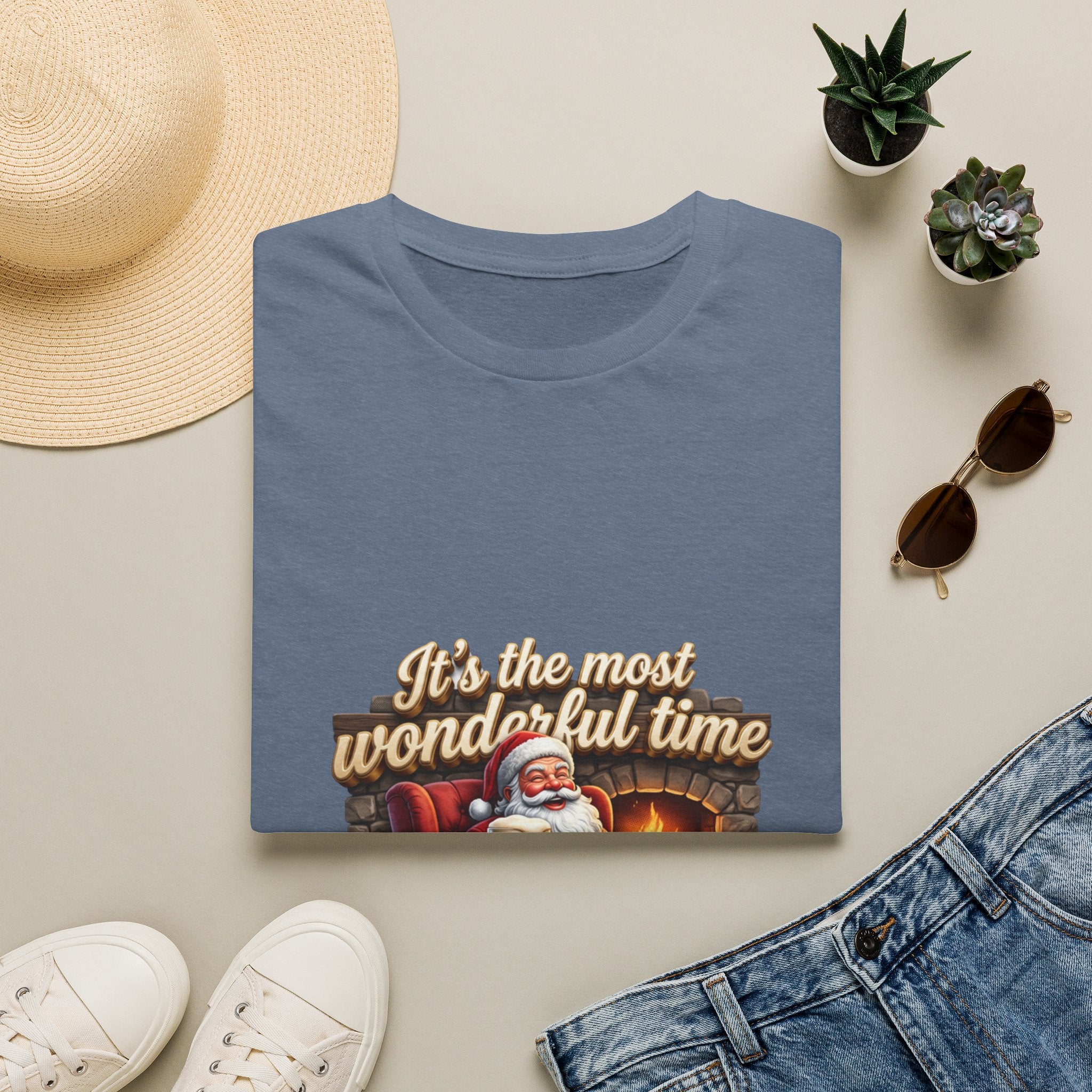 Most Wonderful Time for a Beer Santa print on a Heather Indigo t-shirt, folded beside a straw hat and jeans