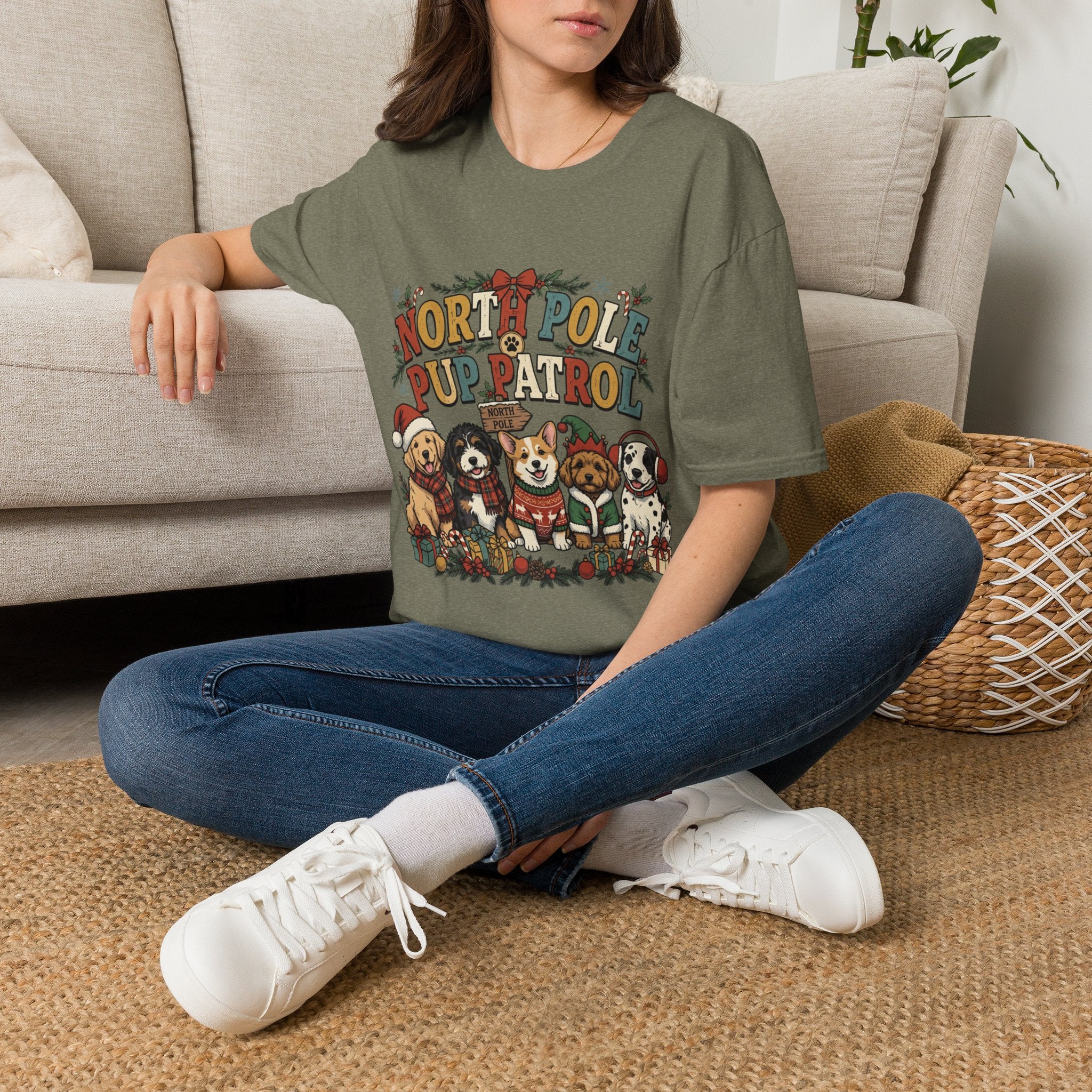 North Pole Pup Patrol Christmas Dogs t-shirt in Heather Military Green, worn by a woman seated on a rug