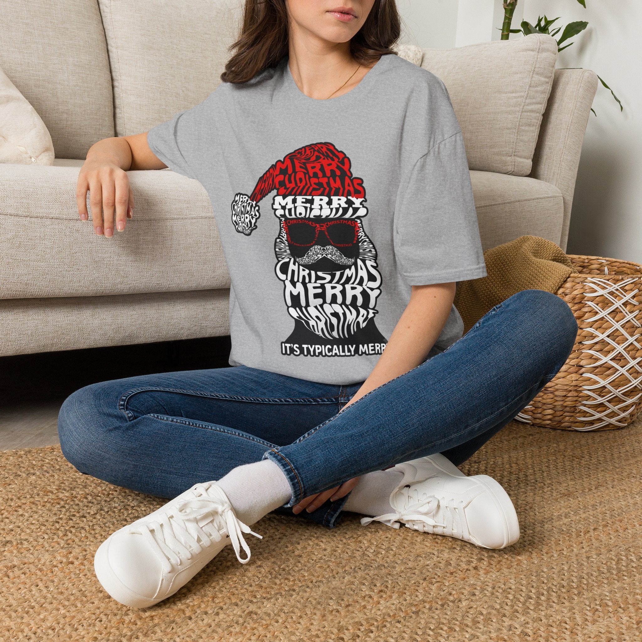Cool Santa Sunglasses Typography Merry t-shirt in Sport Grey, worn by a woman seated on a rug
