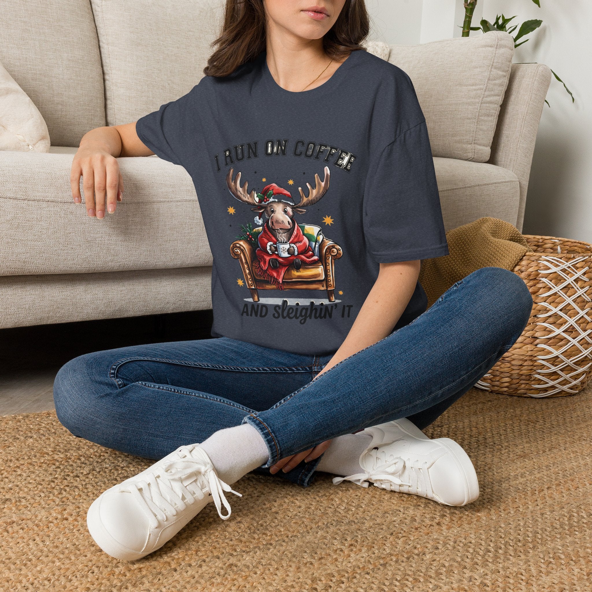 Moose I Run On Coffee and Sleighin' It t-shirt in Heather Navy, worn by a woman seated on a rug
