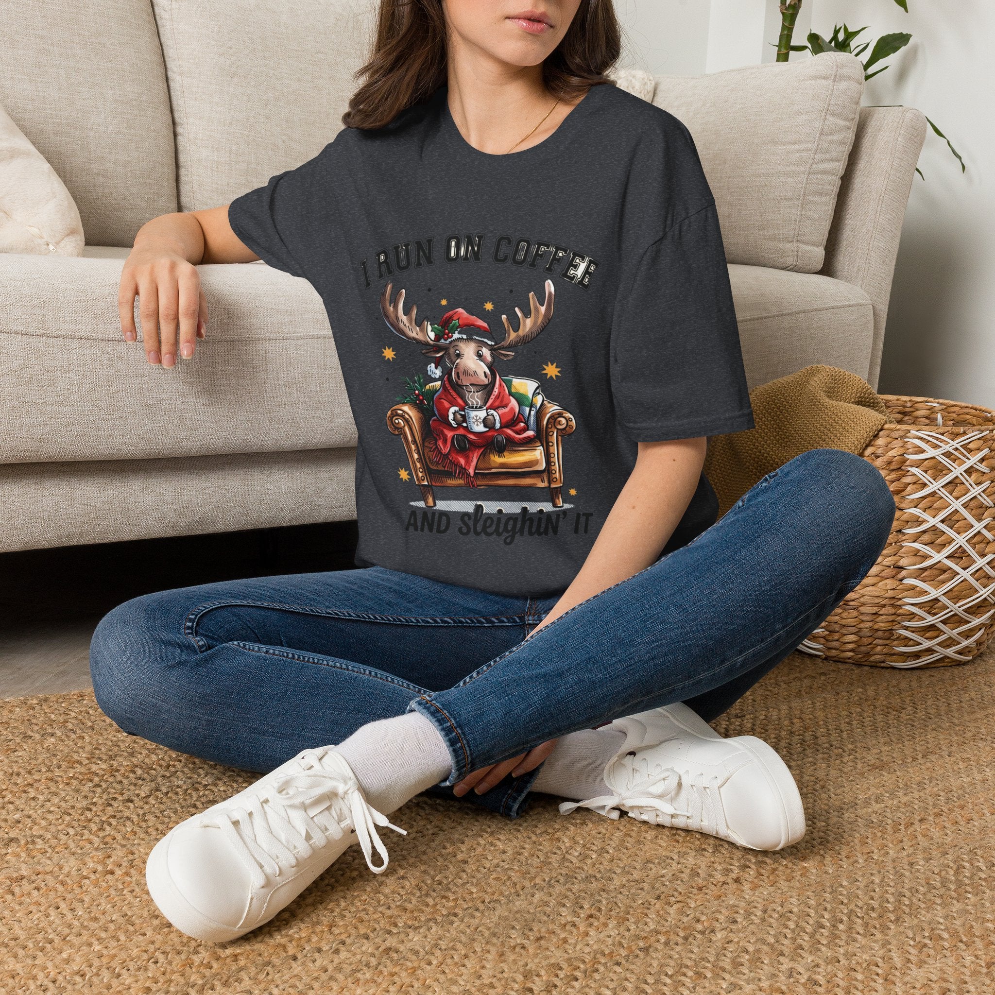 Moose I Run On Coffee and Sleighin' It t-shirt in Dark Heather Grey, worn by a woman seated on a rug