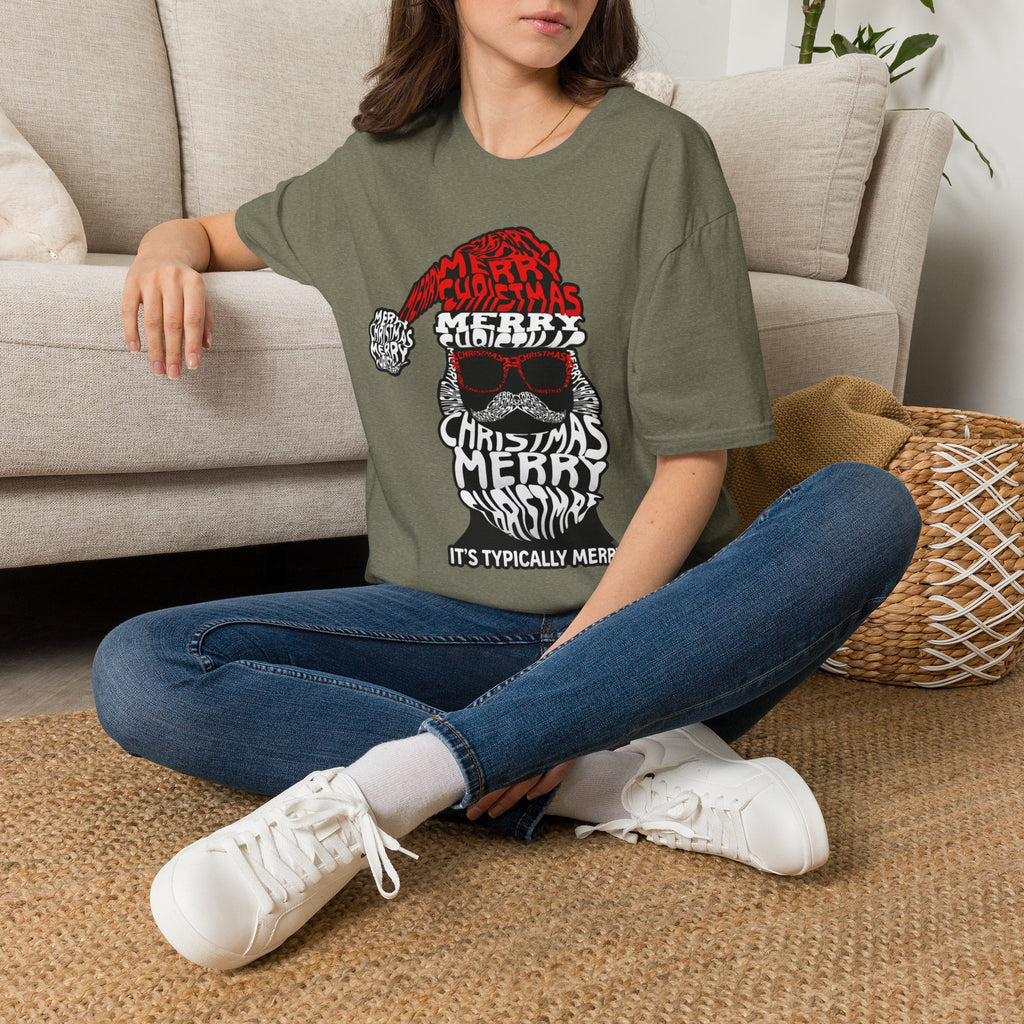 Cool Santa Sunglasses Typography Merry t-shirt in Heather Military Green, worn by a woman seated on a rug