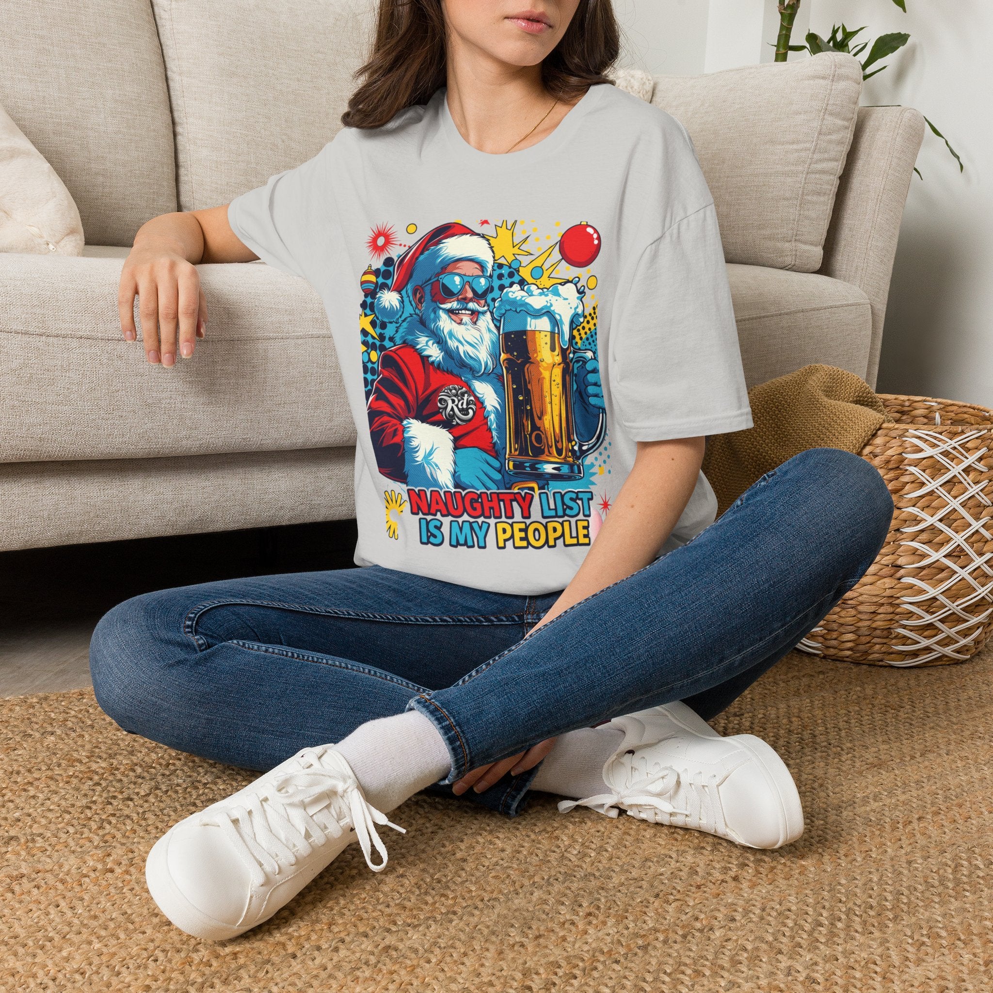 Naughty List Is My People Pop Art Santa Beer t-shirt in Ice Grey, worn by a woman seated on a rug