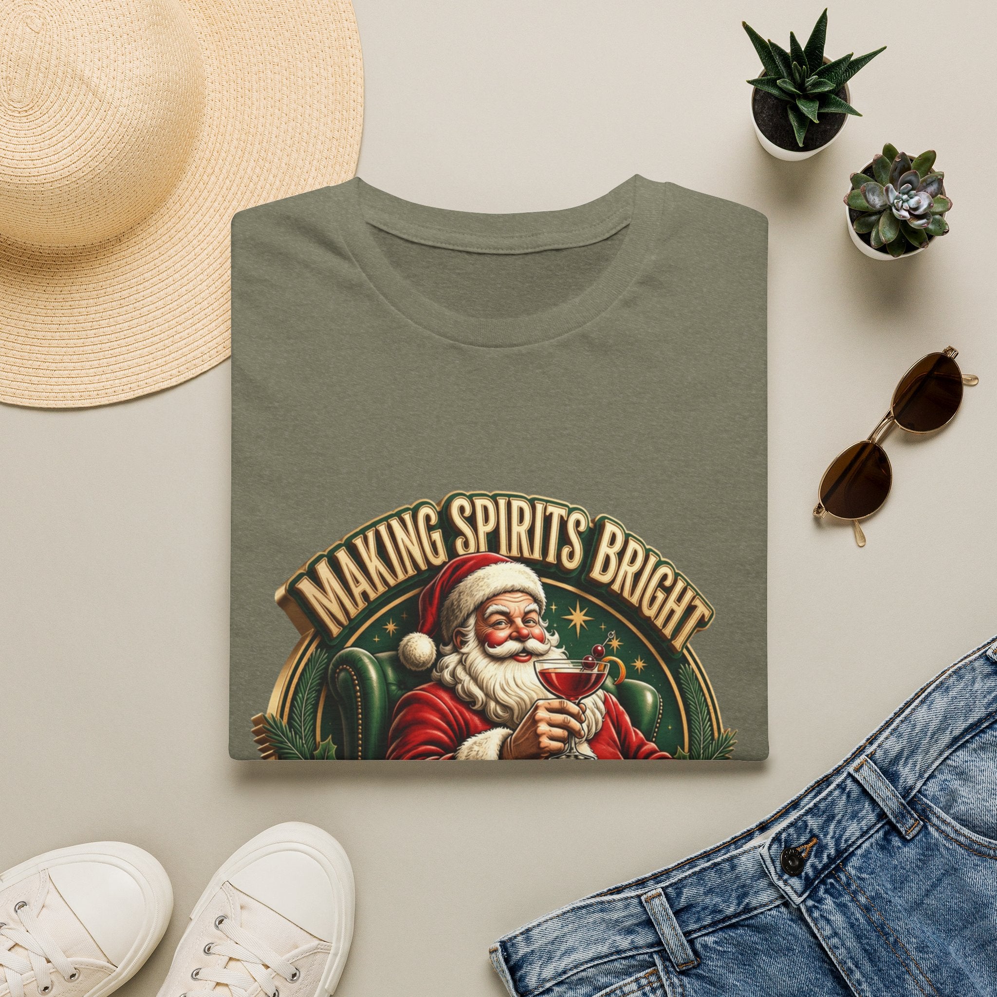 Making Spirits Bright and Stronger Santa print on a Heather Military Green t-shirt, folded beside a straw hat and jeans