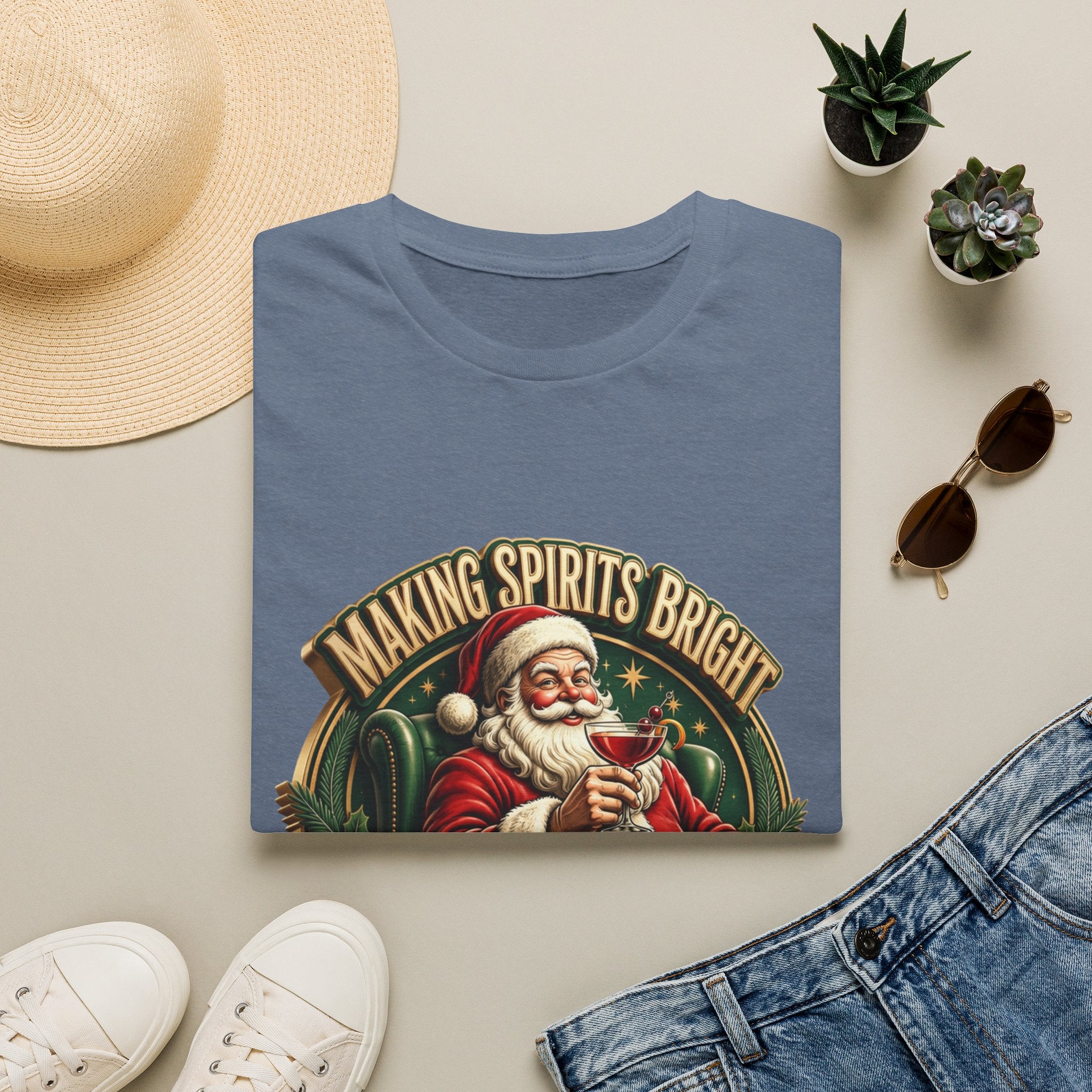 Making Spirits Bright and Stronger Santa print on a Heather Indigo t-shirt, folded beside a straw hat and jeans