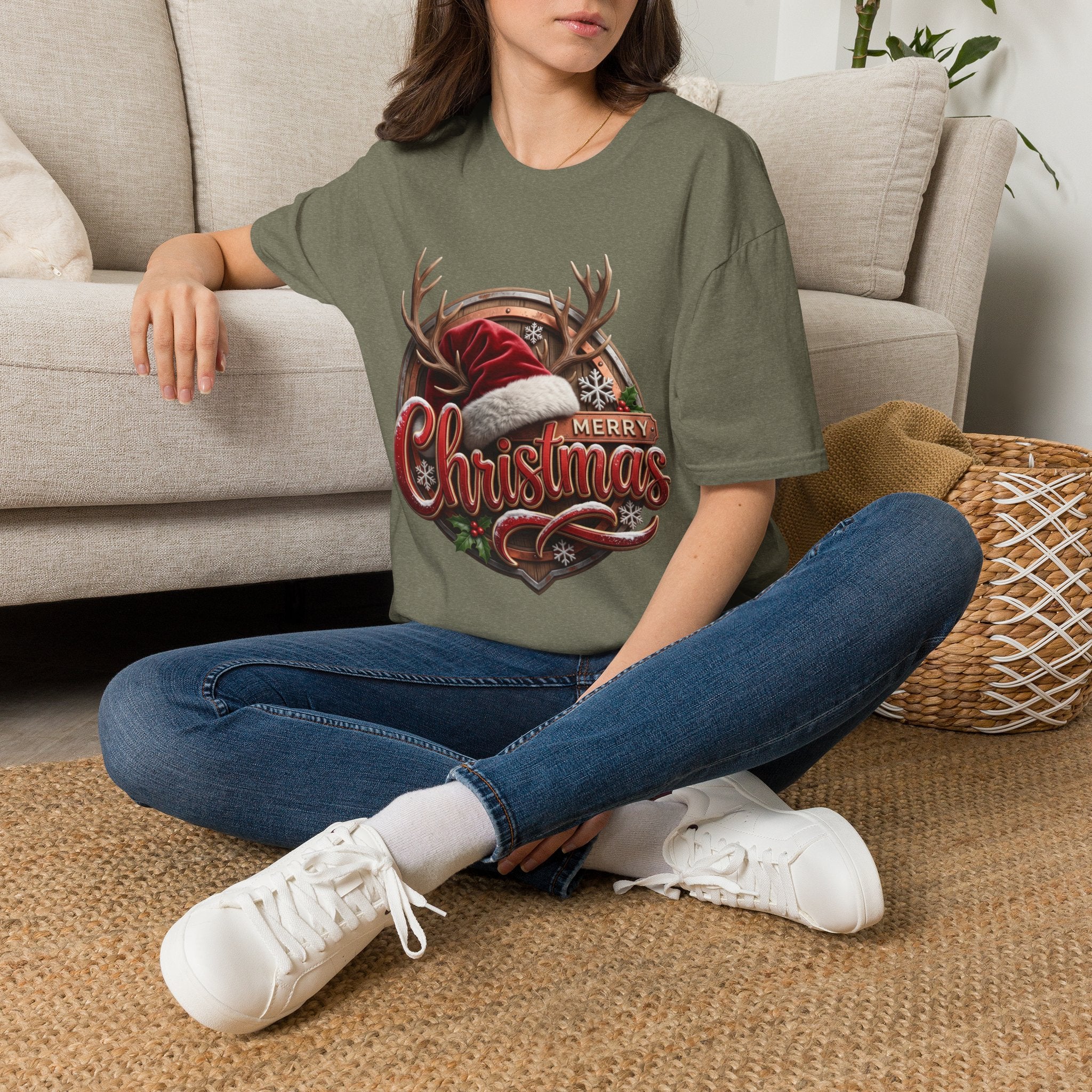 Merry Christmas Vintage Santa Hat & Antlers t-shirt in Heather Military Green, worn by a woman seated on a rug