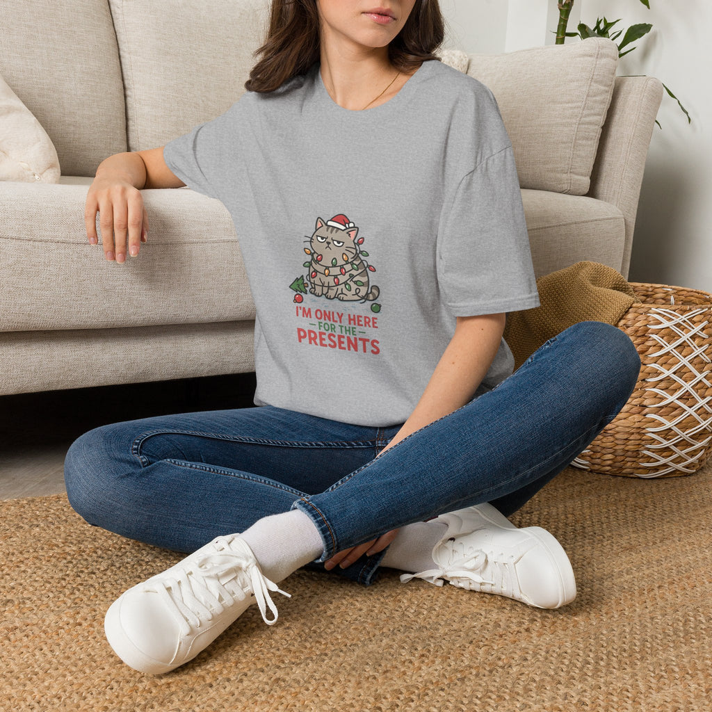 Funny Cat I'm Only Here for the Presents t-shirt in Sport Grey, worn by a woman seated on a rug