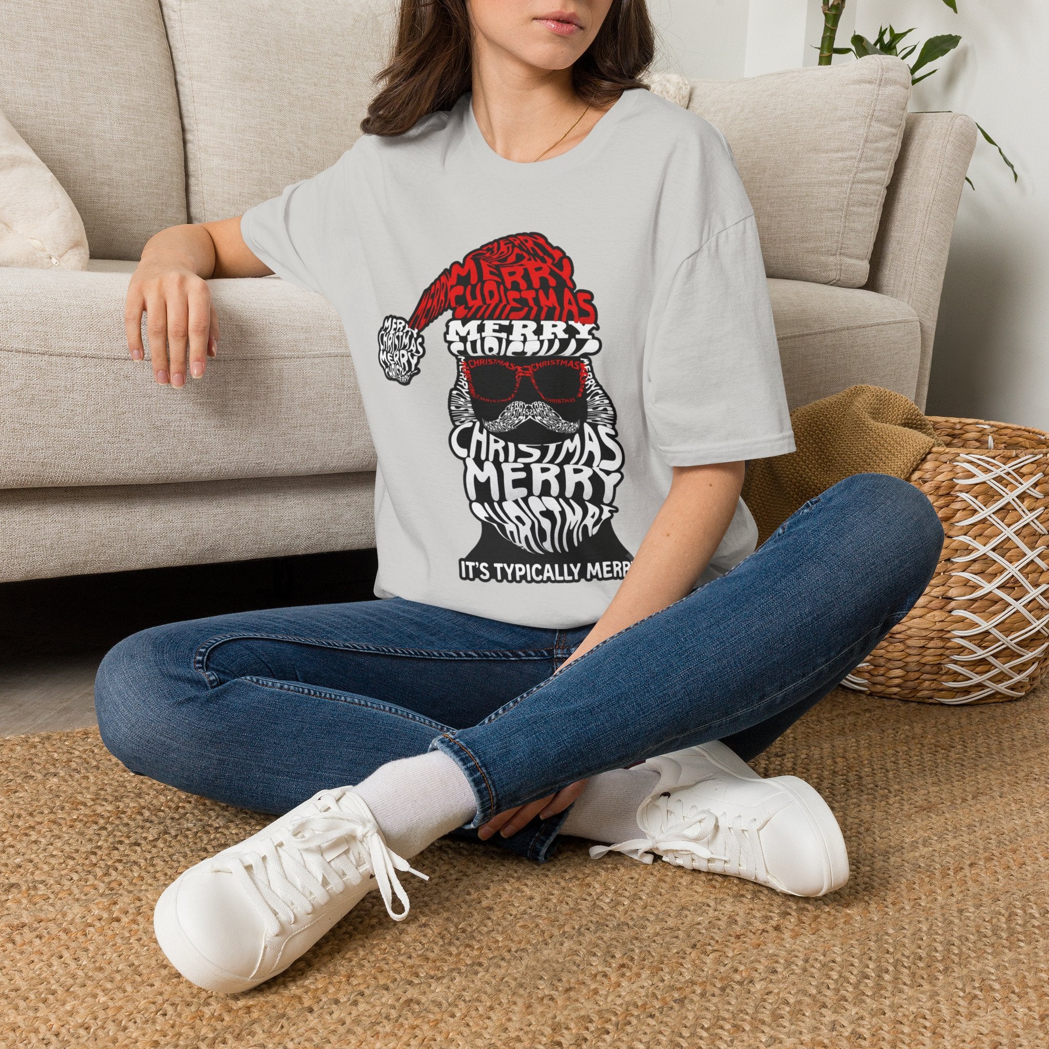 Cool Santa Sunglasses Typography Merry t-shirt in Ice Grey, worn by a woman seated on a rug