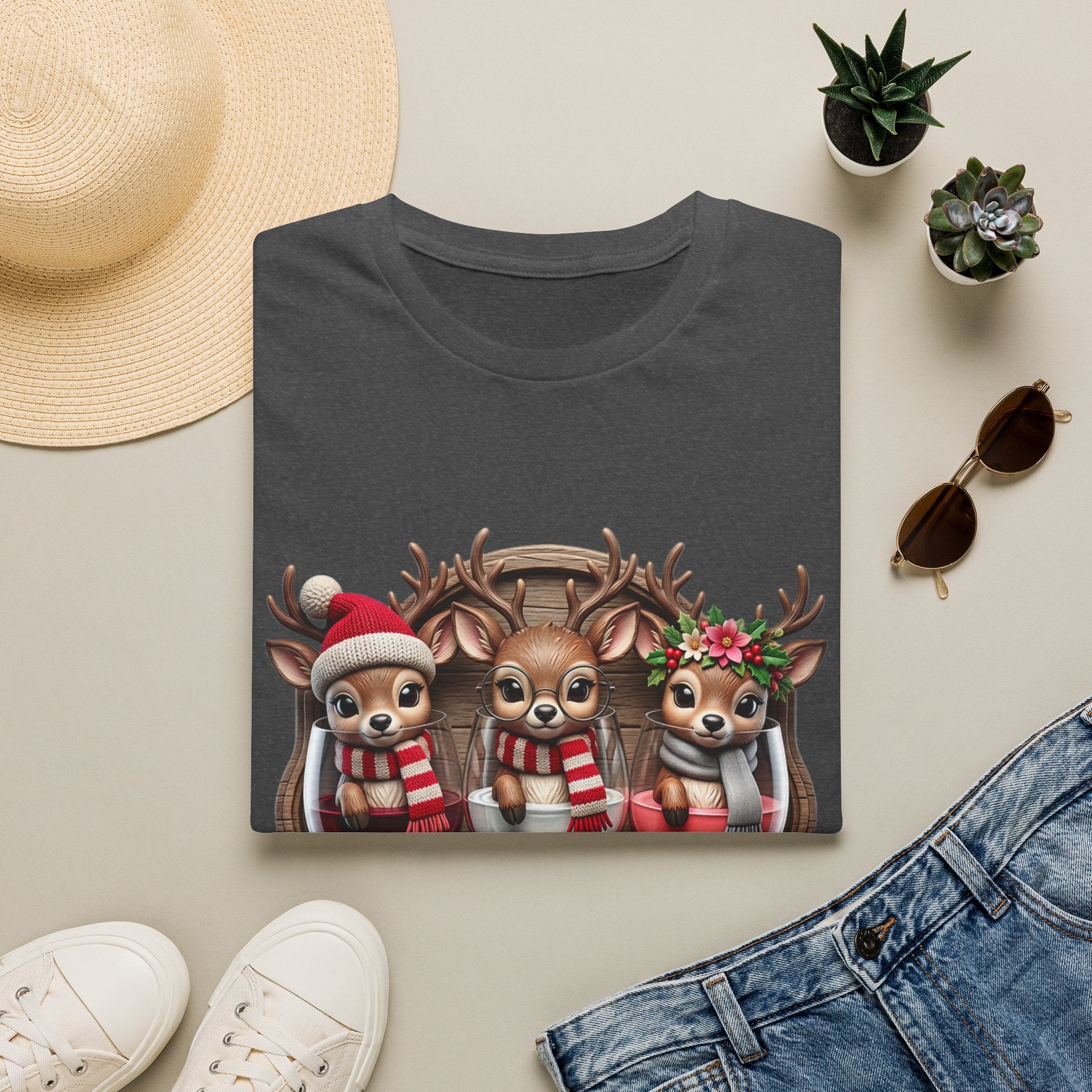 Drink Drank Drunk Reindeer Wine Trio print on a Dark Heather t-shirt, folded beside a straw hat and jeans