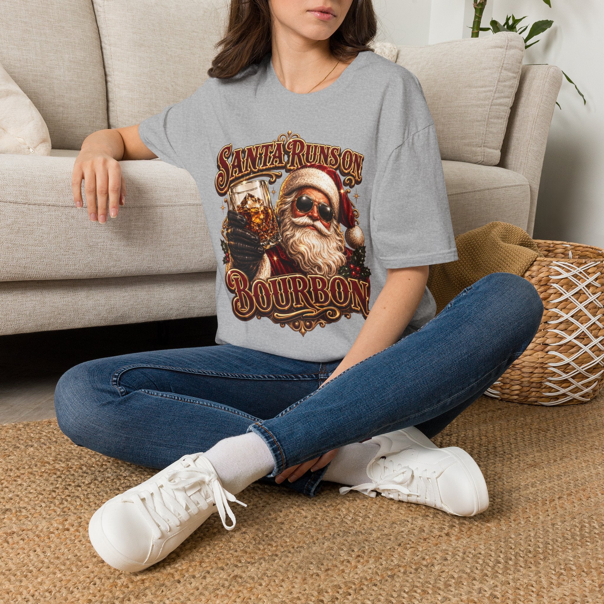 Santa Runs on Bourbon Vintage Whiskey t-shirt in Sport Grey, worn by a woman seated on a rug