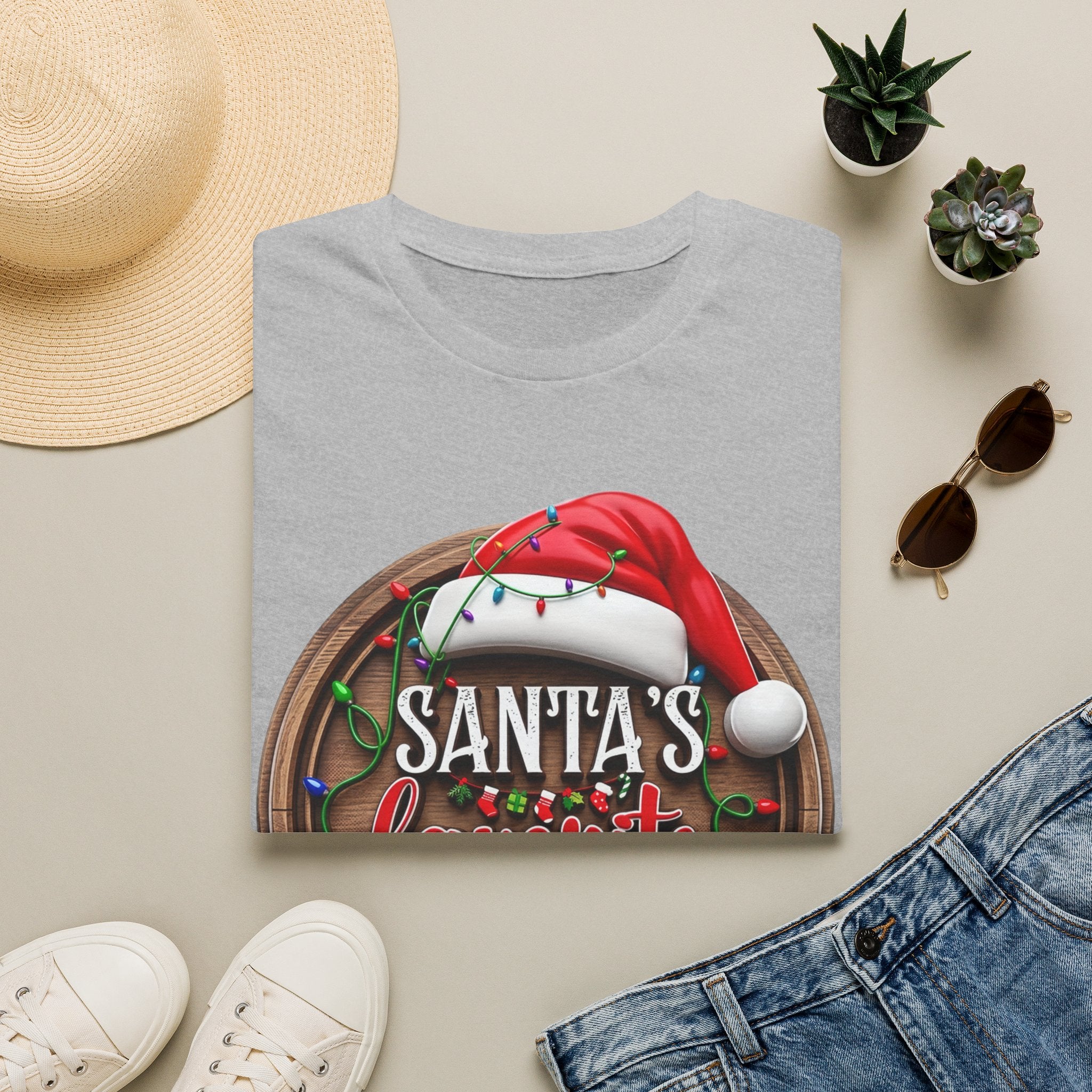 Santa's Favorite Office Staff print on a Sport Grey t-shirt, folded beside a straw hat and jeans
