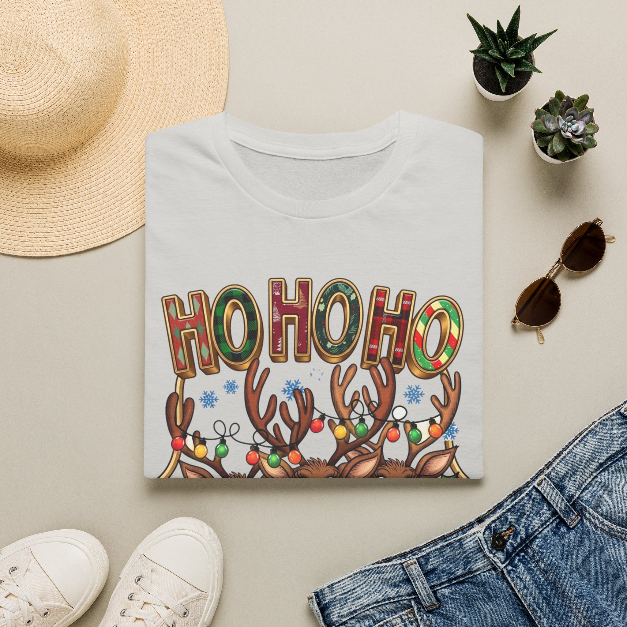 Reindeer Trio Ho Ho Ho Christmas Lights print on an Ice Grey t-shirt, folded beside a straw hat and jeans