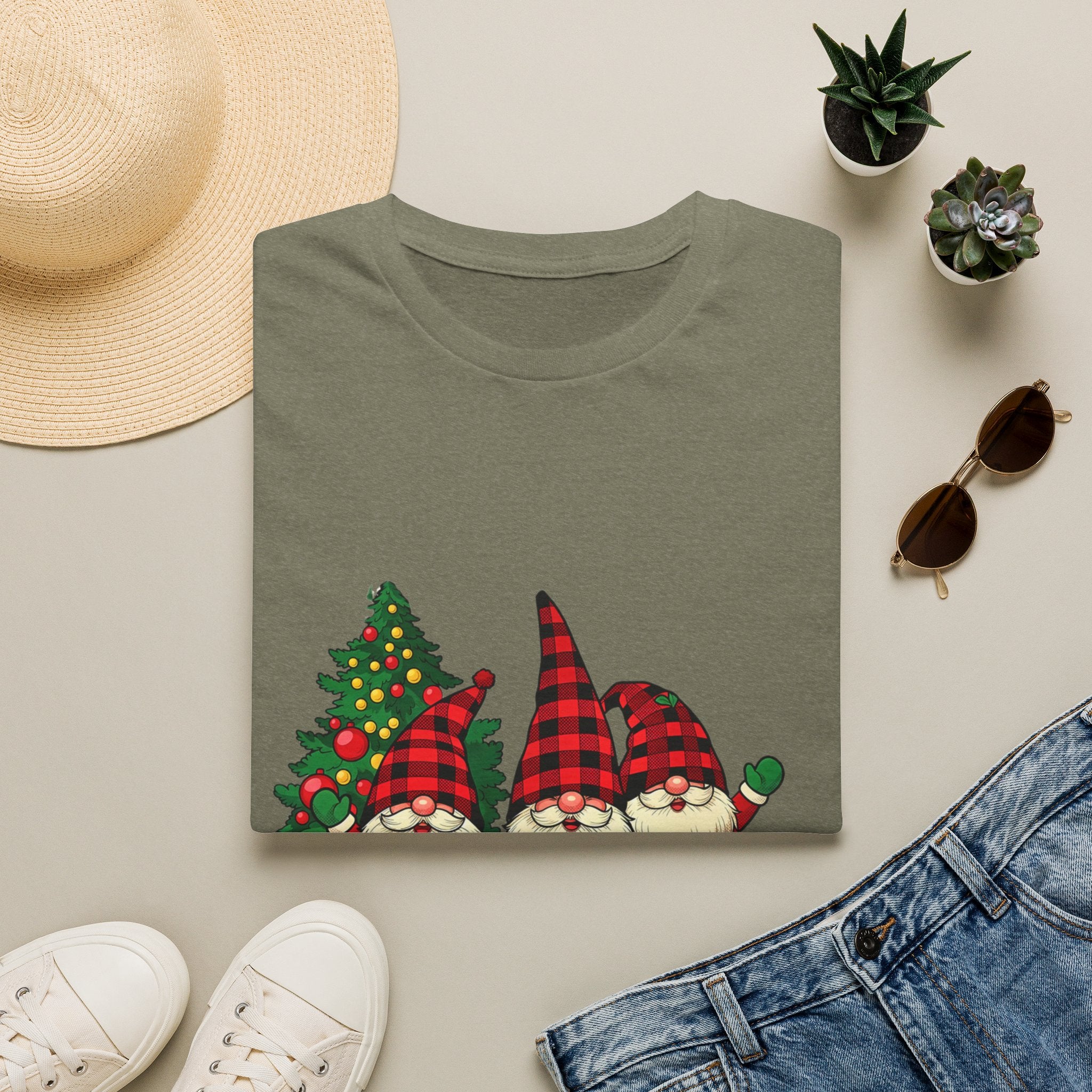 Buffalo Plaid Gnomes Red Truck print on a Heather Military Green t-shirt, folded beside a straw hat and jeans