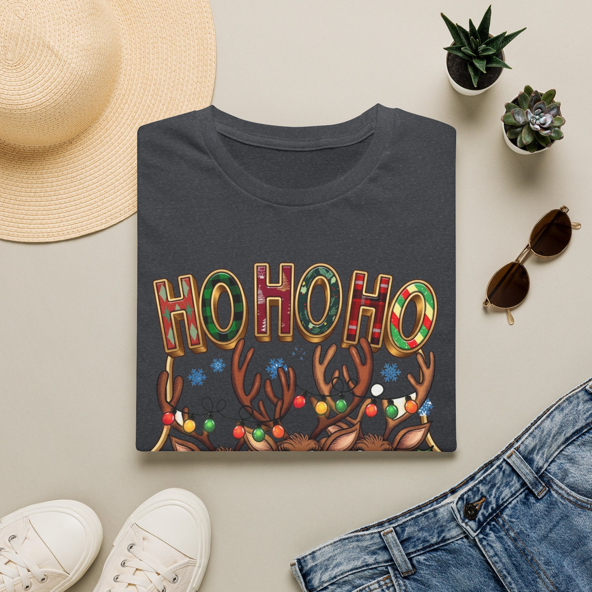 Reindeer Trio Ho Ho Ho Christmas Lights print on a Dark Heather Grey t-shirt, folded beside a straw hat and jeans