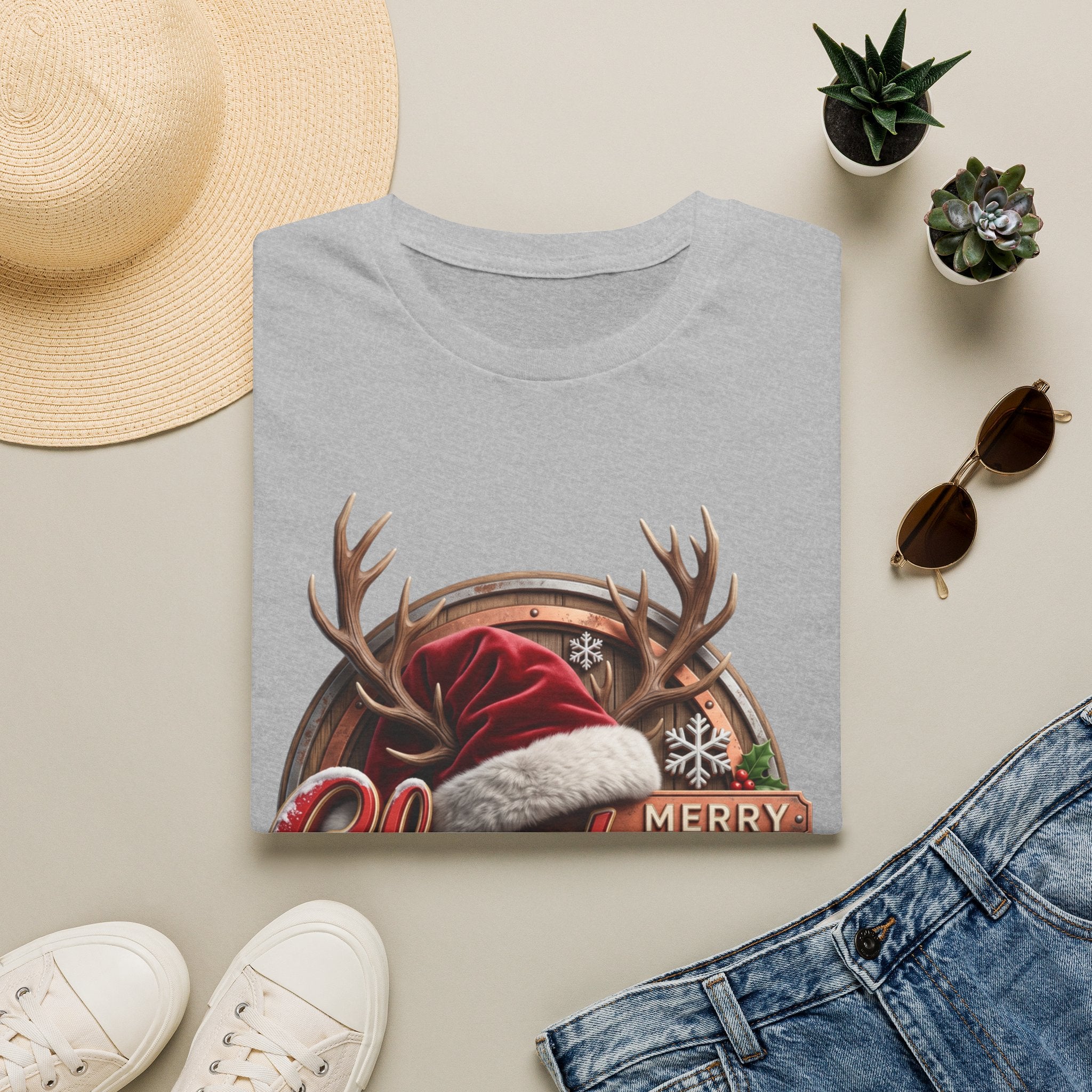 Merry Christmas Vintage Santa Hat & Antlers print on a Sport Grey t-shirt, folded beside a straw hat and jeans