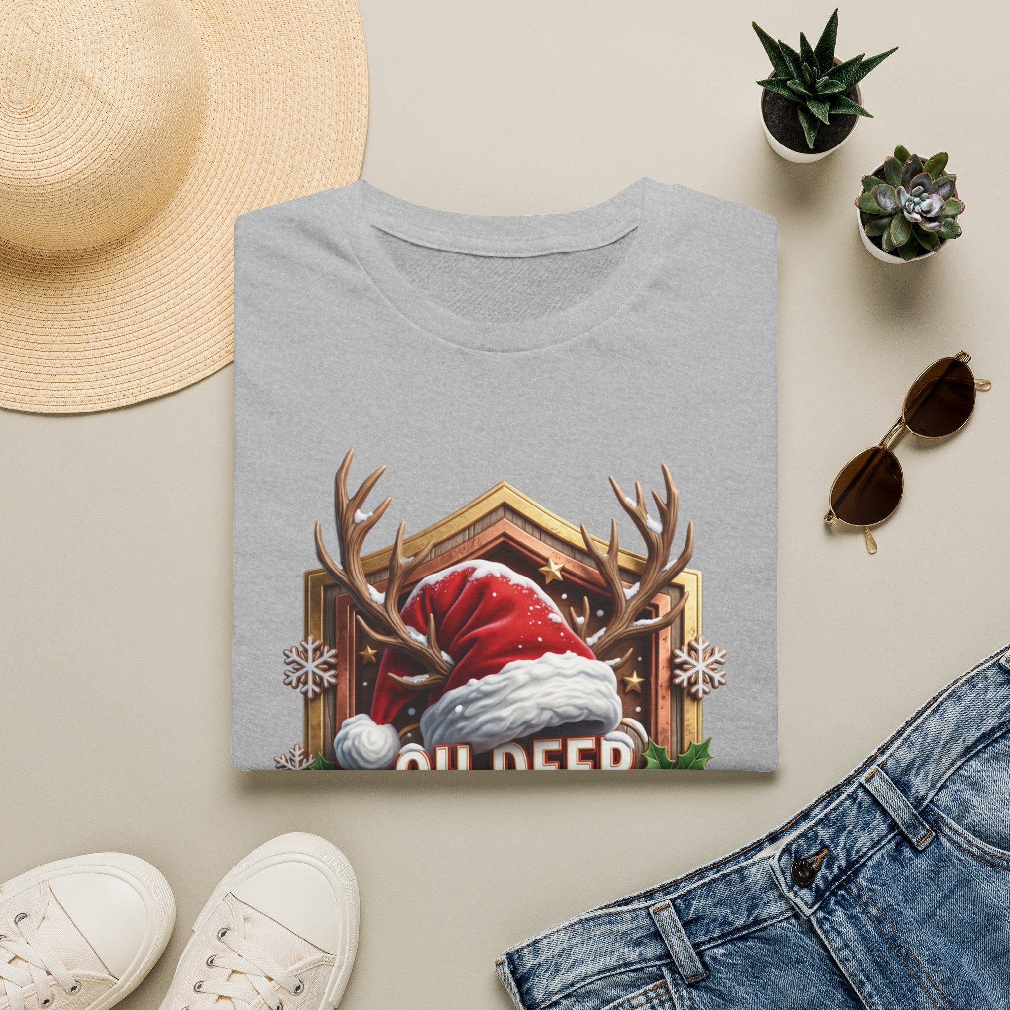 Oh Deer It's Christmas Looks a Lot Like Cocktails print on a Sport Grey t-shirt, folded beside a straw hat and jeans