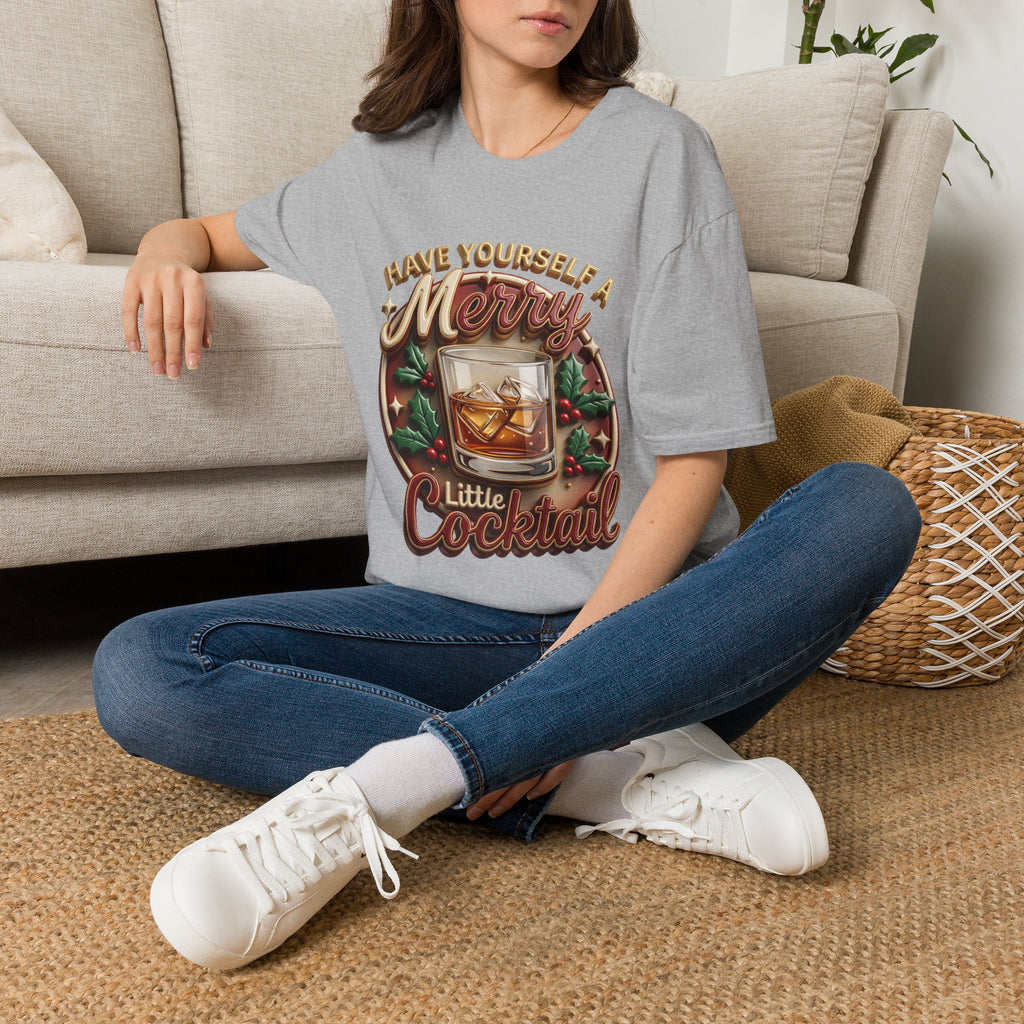 Have Yourself a Merry Little Cocktail t-shirt in Sport Grey, worn by a woman seated on a rug