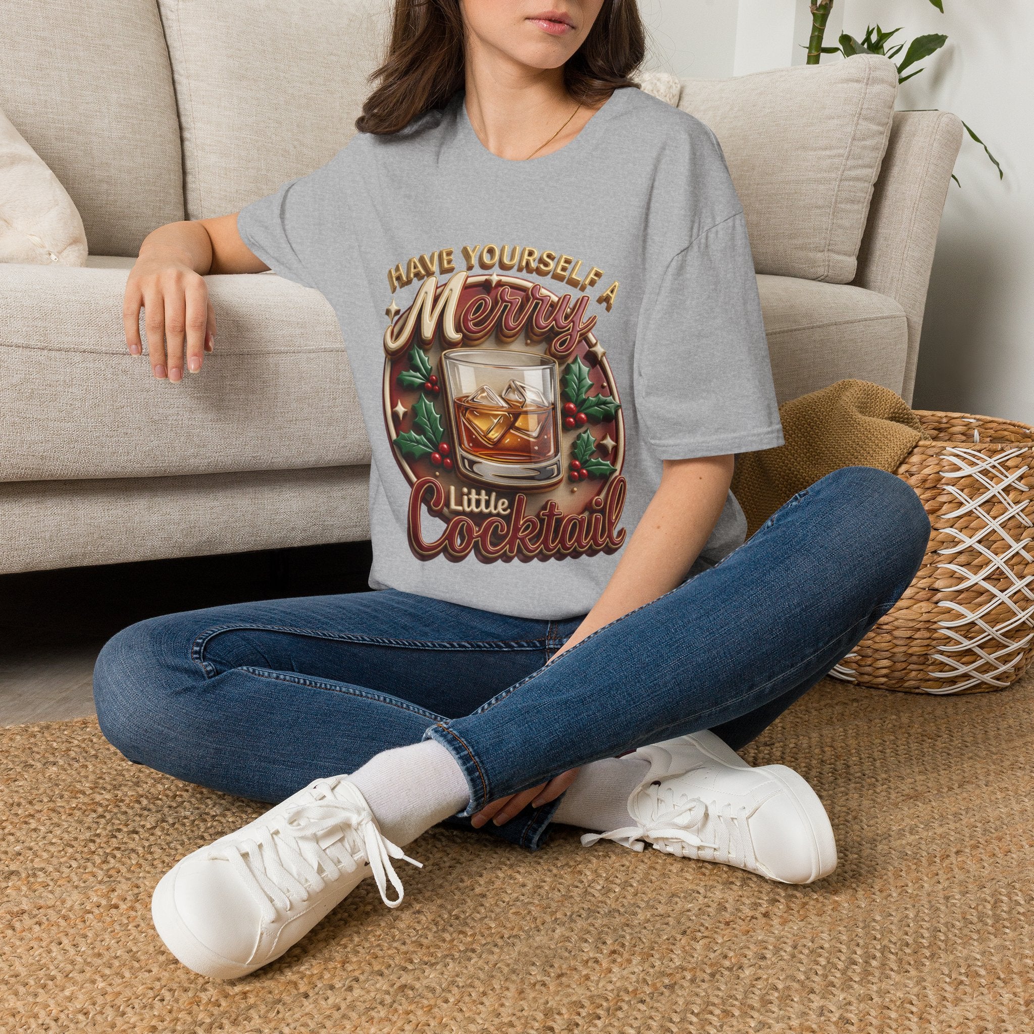 Have Yourself a Merry Little Cocktail t-shirt in Sport Grey, worn by a woman seated on a rug