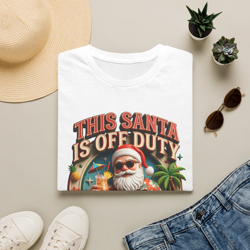This Santa Is Off Duty Cocktail Club print on a White t-shirt, folded beside a straw hat and jeans