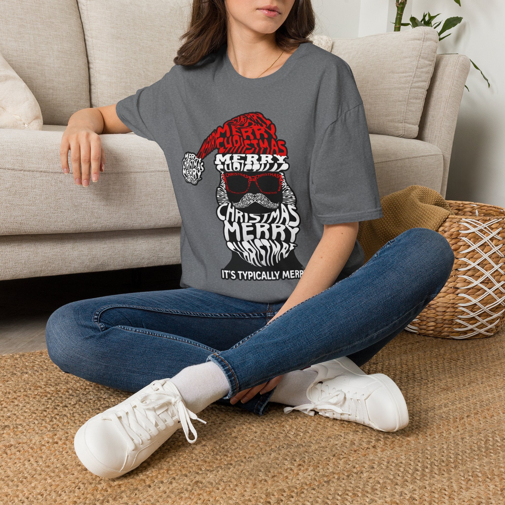 Cool Santa Sunglasses Typography Merry t-shirt in Graphite Heather, worn by a woman seated on a rug