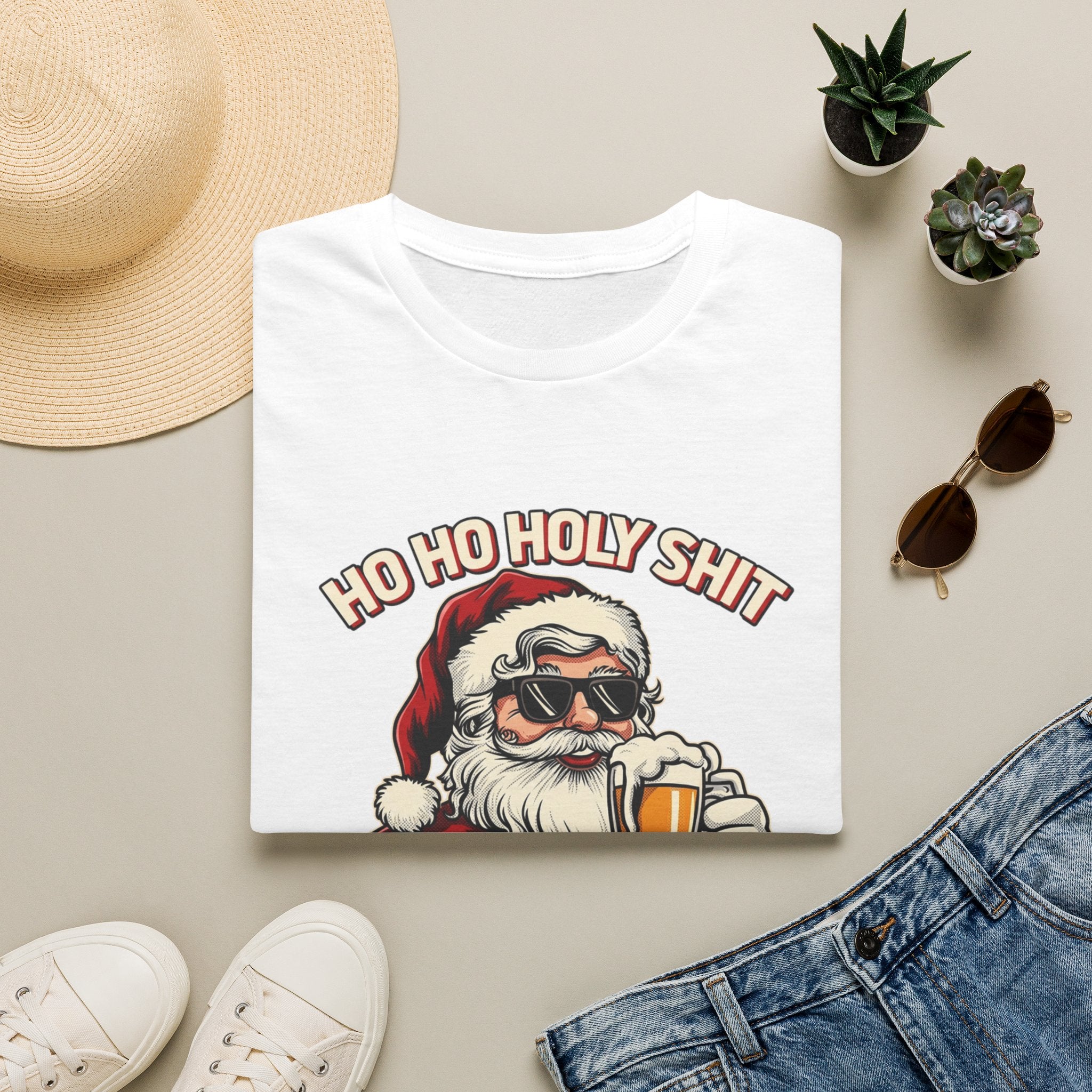 Ho Ho Holy Sh*t I Need a Beer print on a White t-shirt, folded beside a straw hat and jeans