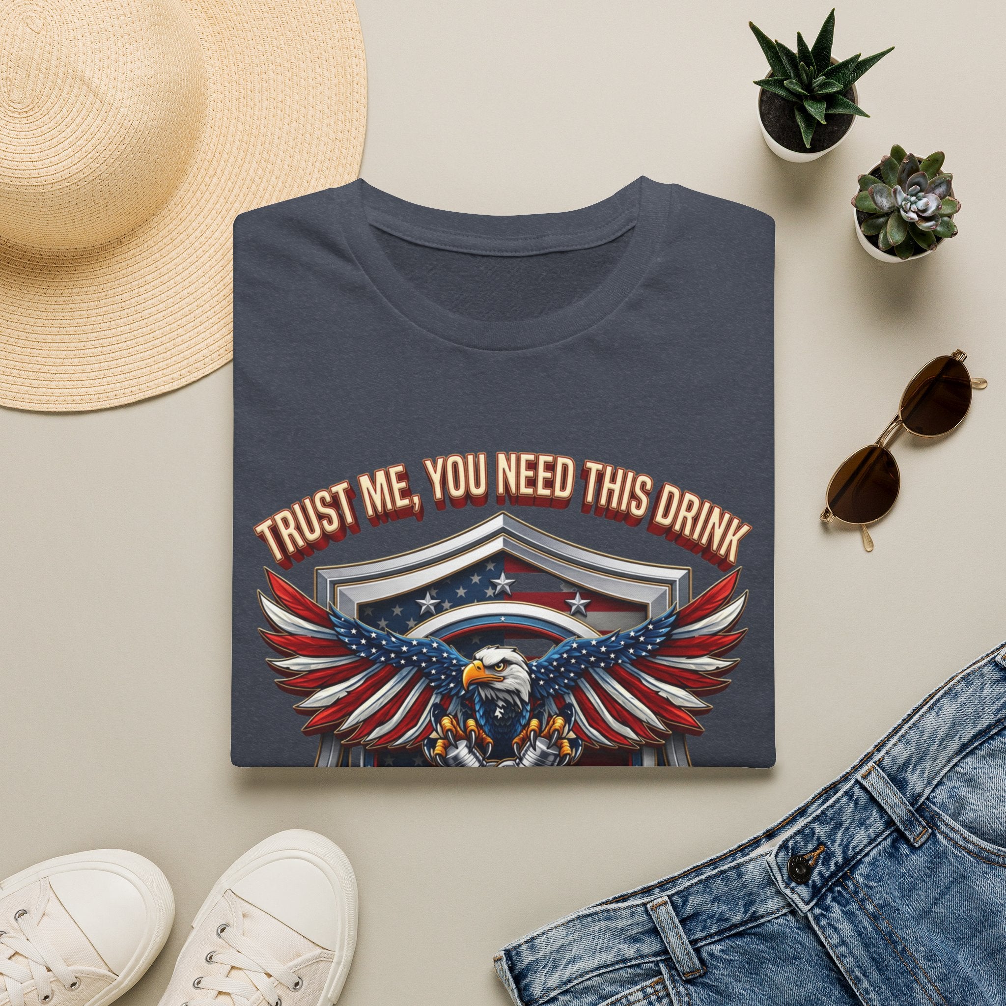 Bartender Eagle Trust Me You Need This Drink print on a Heather Navy t-shirt, folded beside a straw hat and jeans