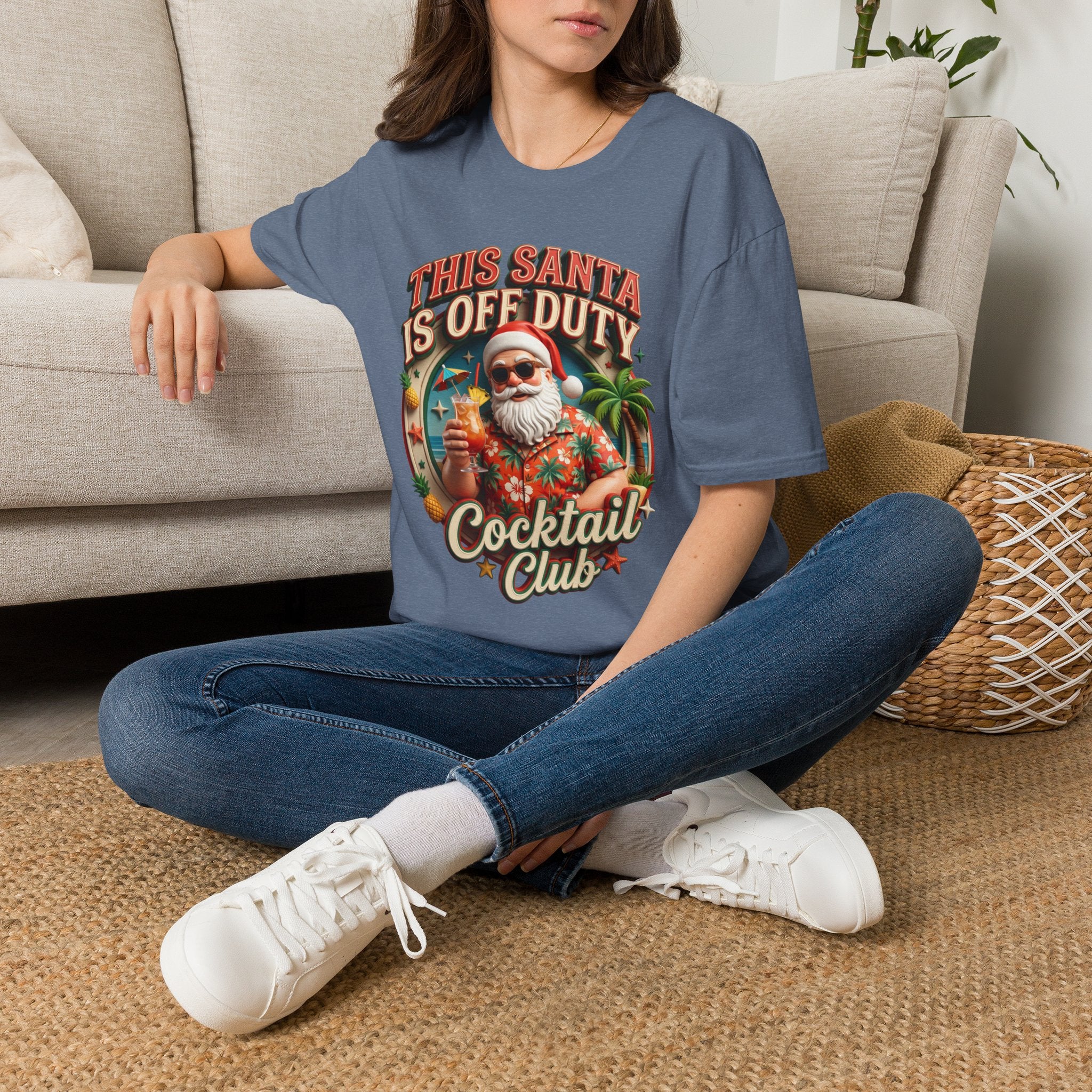 This Santa Is Off Duty Cocktail Club t-shirt in Heather Indigo, worn by a woman seated on a rug