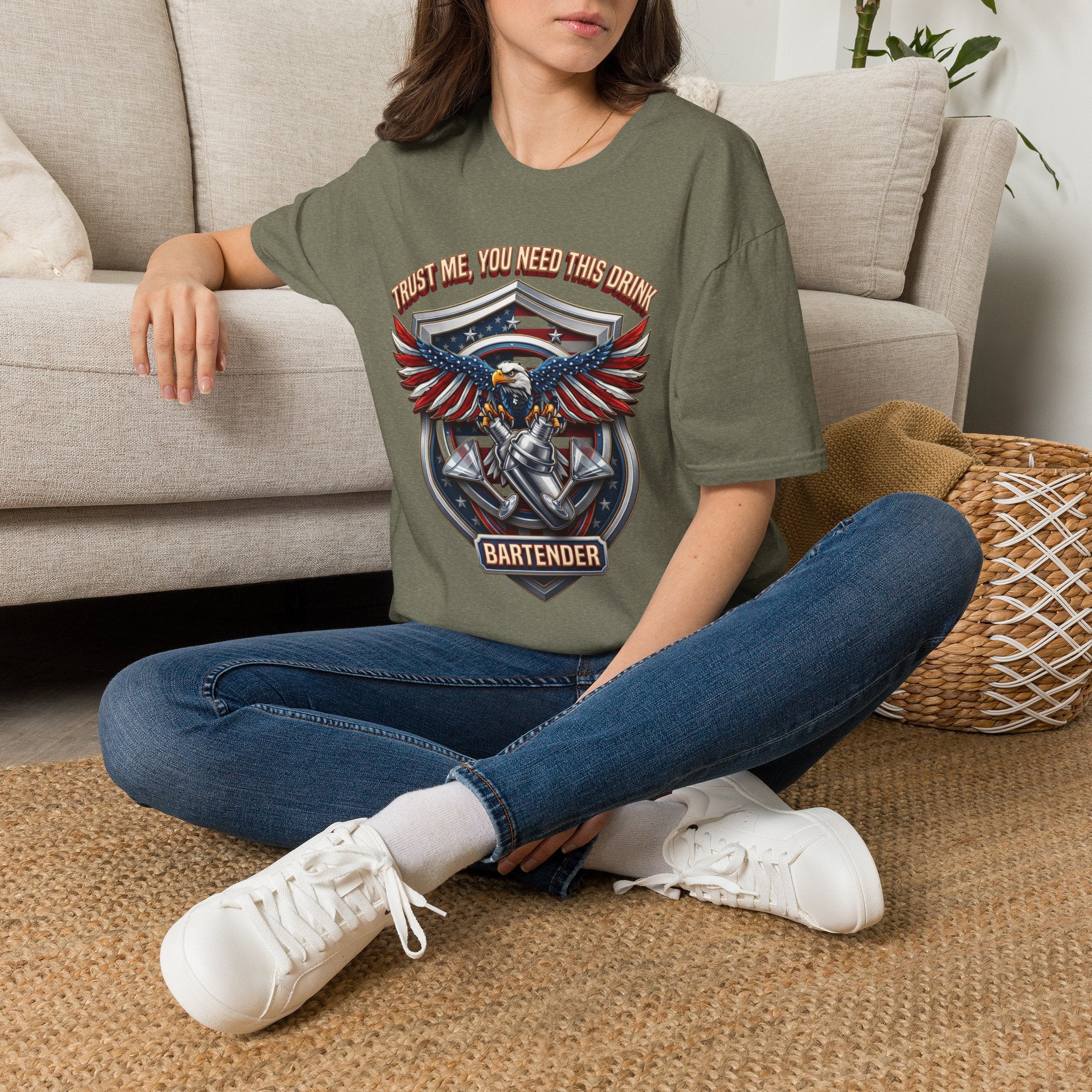 Bartender Eagle Trust Me You Need This Drink t-shirt in Heather Military Green, worn by a woman seated on a rug