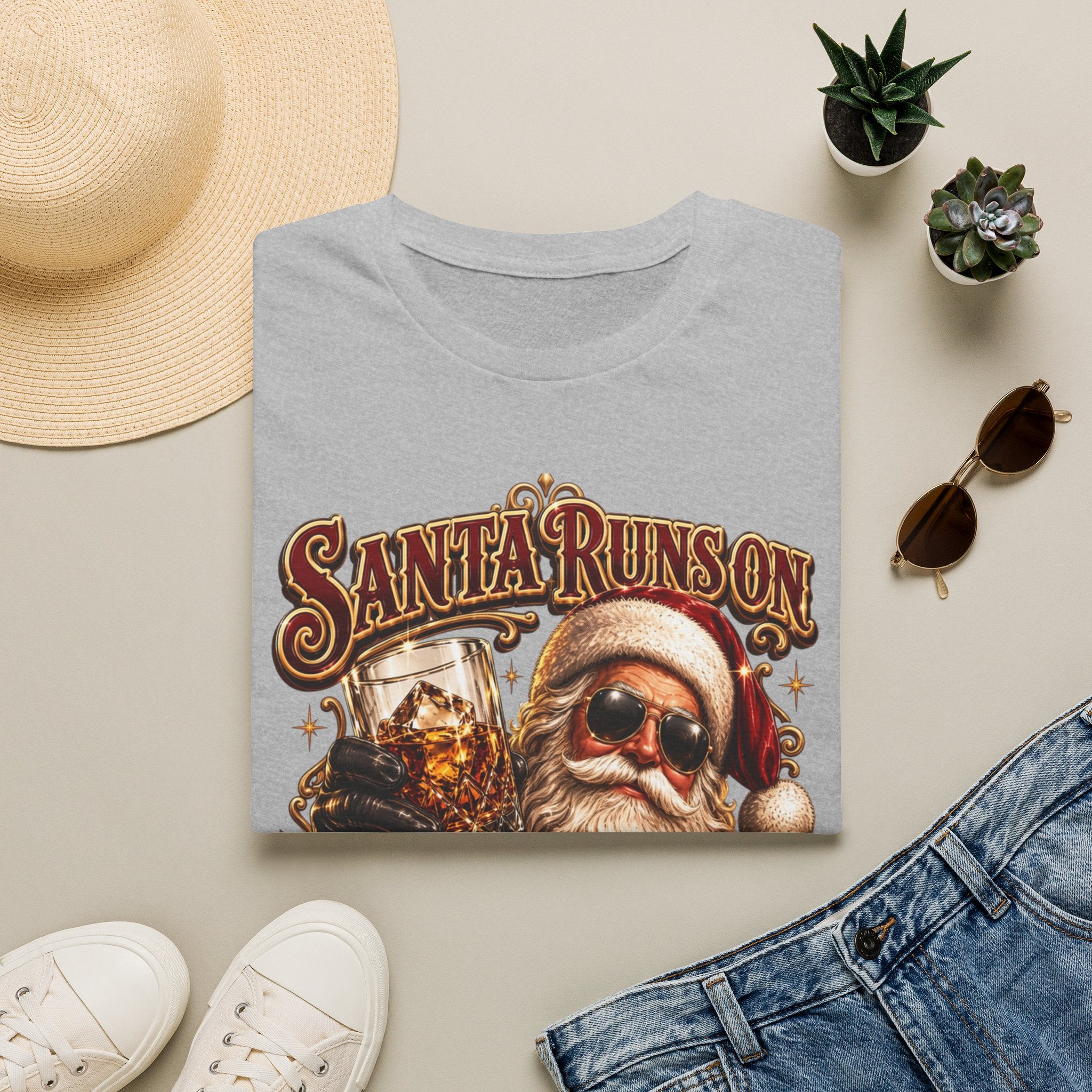 Santa Runs on Bourbon Vintage Whiskey print on a Sport Grey t-shirt, folded beside a straw hat and jeans