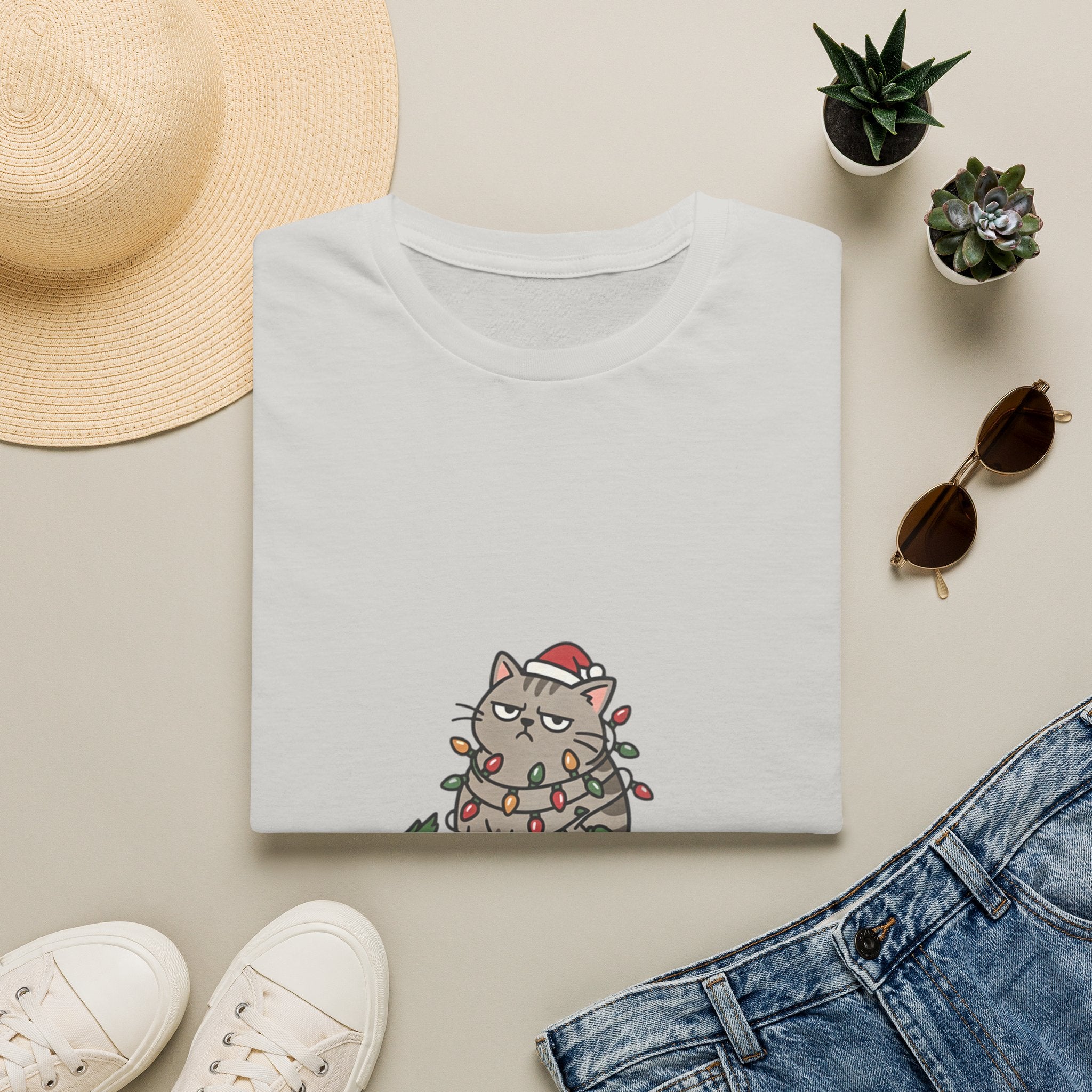 Funny Cat I'm Only Here for the Presents print on an Ice Grey t-shirt, folded beside a straw hat and jeans