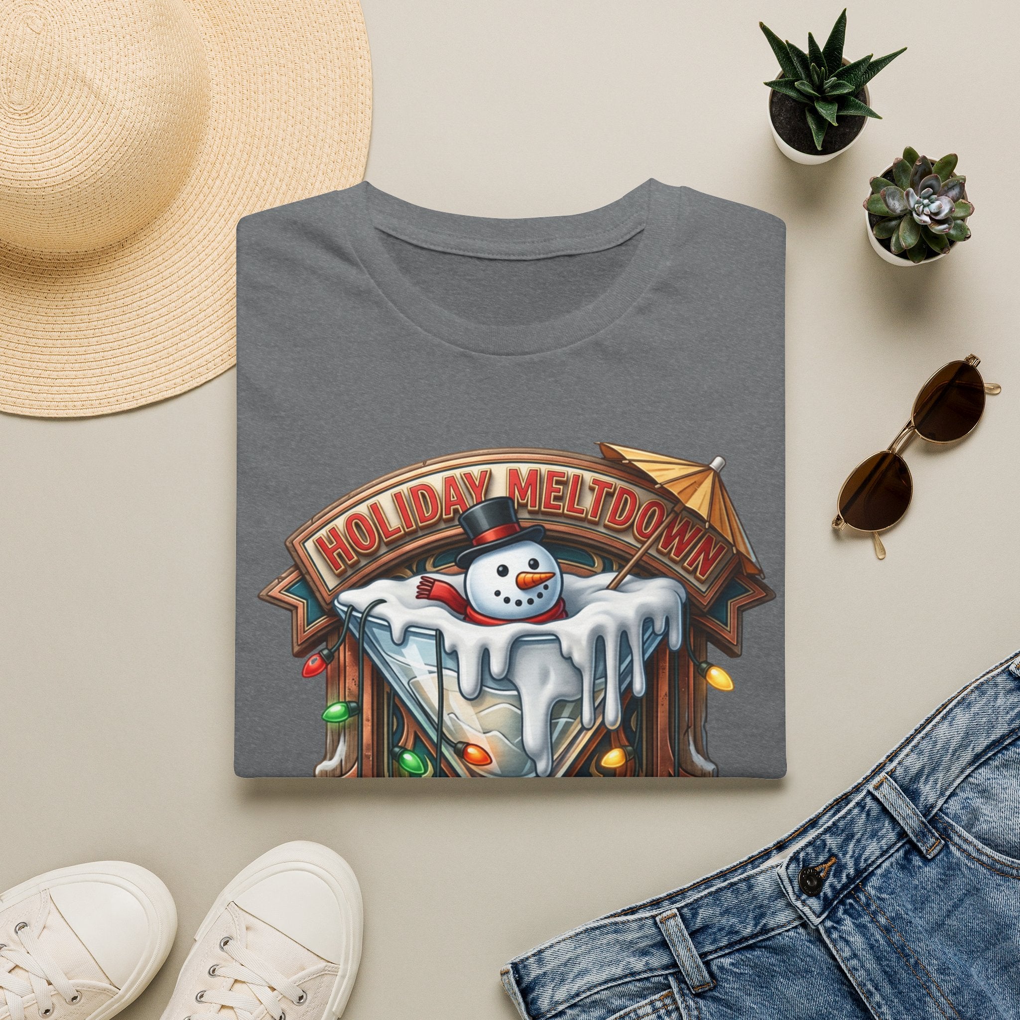 Holiday Meltdown Snowman Martini print on a Graphite Heather t-shirt, folded beside a straw hat and jeans