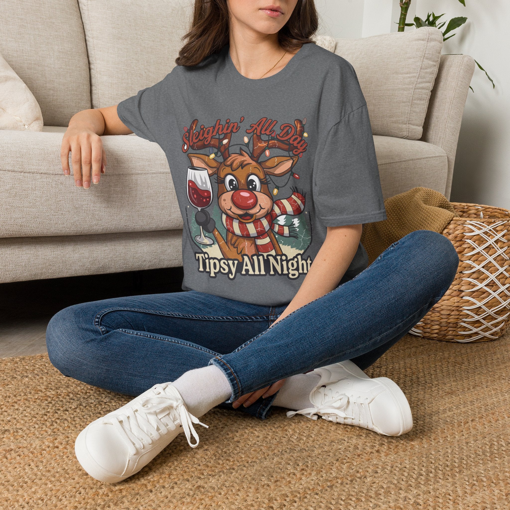 Reindeer Sleighin' All Day Tipsy All Night t-shirt in Graphite Heather, worn by a woman seated on a rug