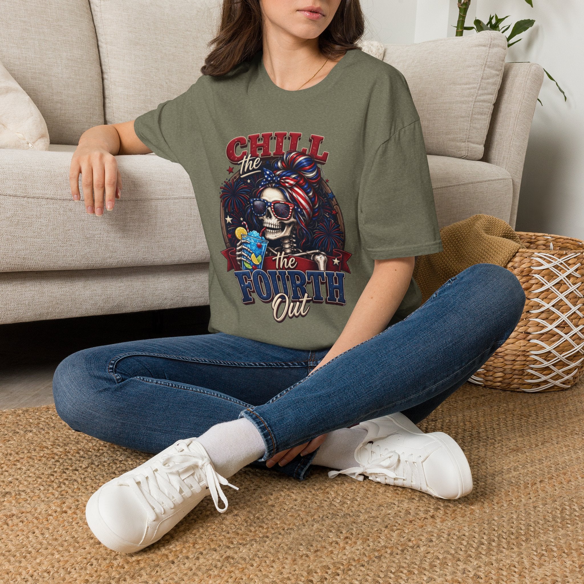 Chill the Fourth Out Patriotic Skeleton 4th of July t-shirt in Heather Military Green, worn by a woman seated on a rug