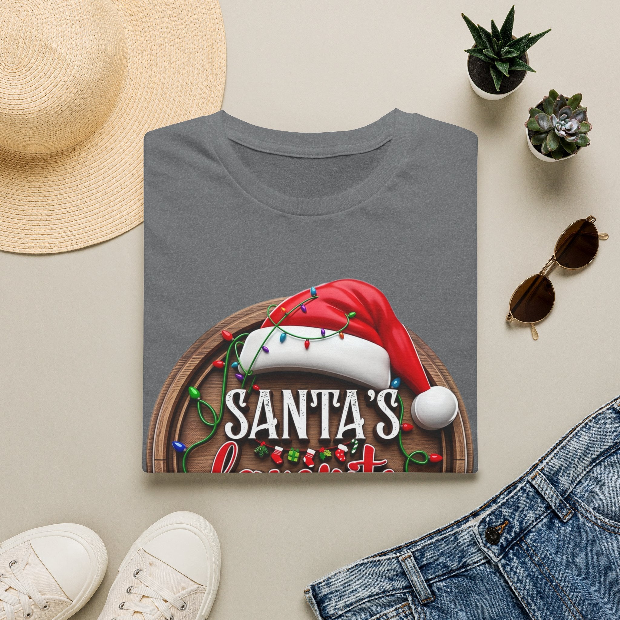 Santa's Favorite Office Staff print on a Graphite Heather t-shirt, folded beside a straw hat and jeans