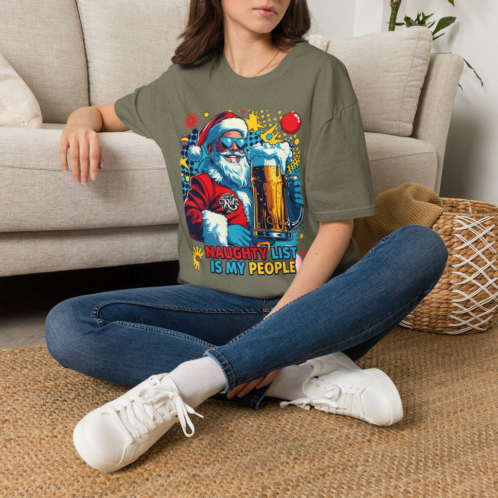 Naughty List Is My People Pop Art Santa Beer t-shirt in Heather Military Green, worn by a woman seated on a rug