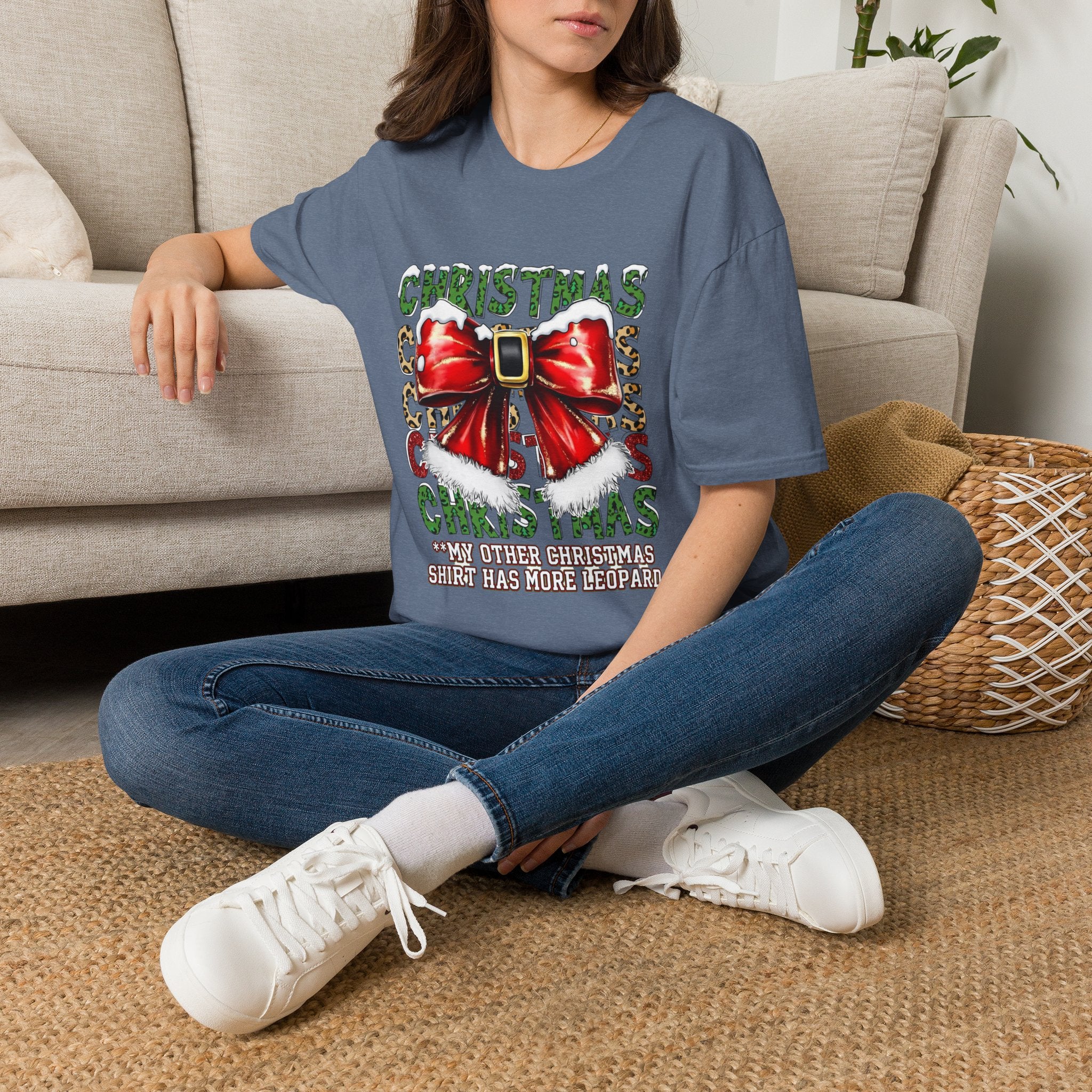 Stacked Christmas Leopard Print Santa Belt Bow t-shirt in Heather Indigo, worn by a woman seated on a rug