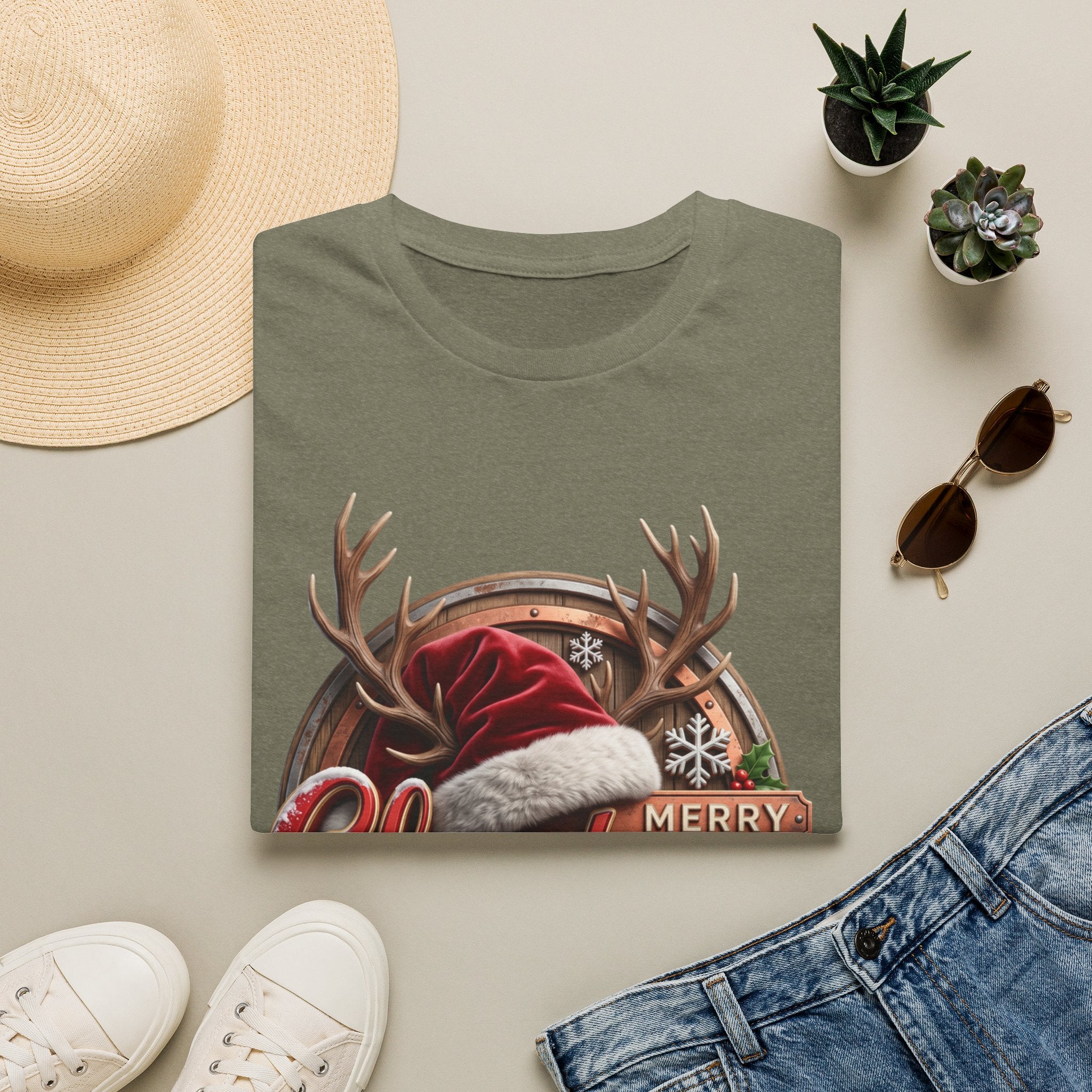 Merry Christmas Vintage Santa Hat & Antlers print on a Heather Military Green t-shirt, folded beside a straw hat and jeans